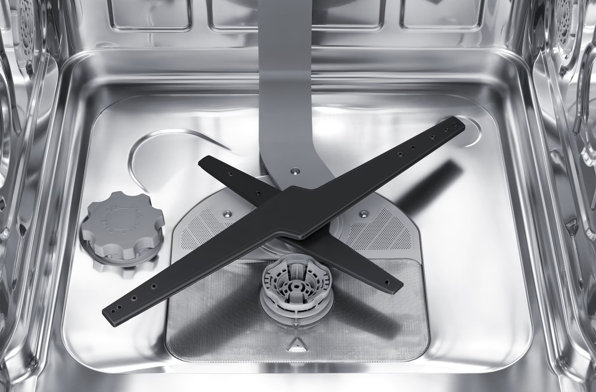 Wnętrze zmywarki z ramieniem spryskującym i pokrywą pojemnika na sól.