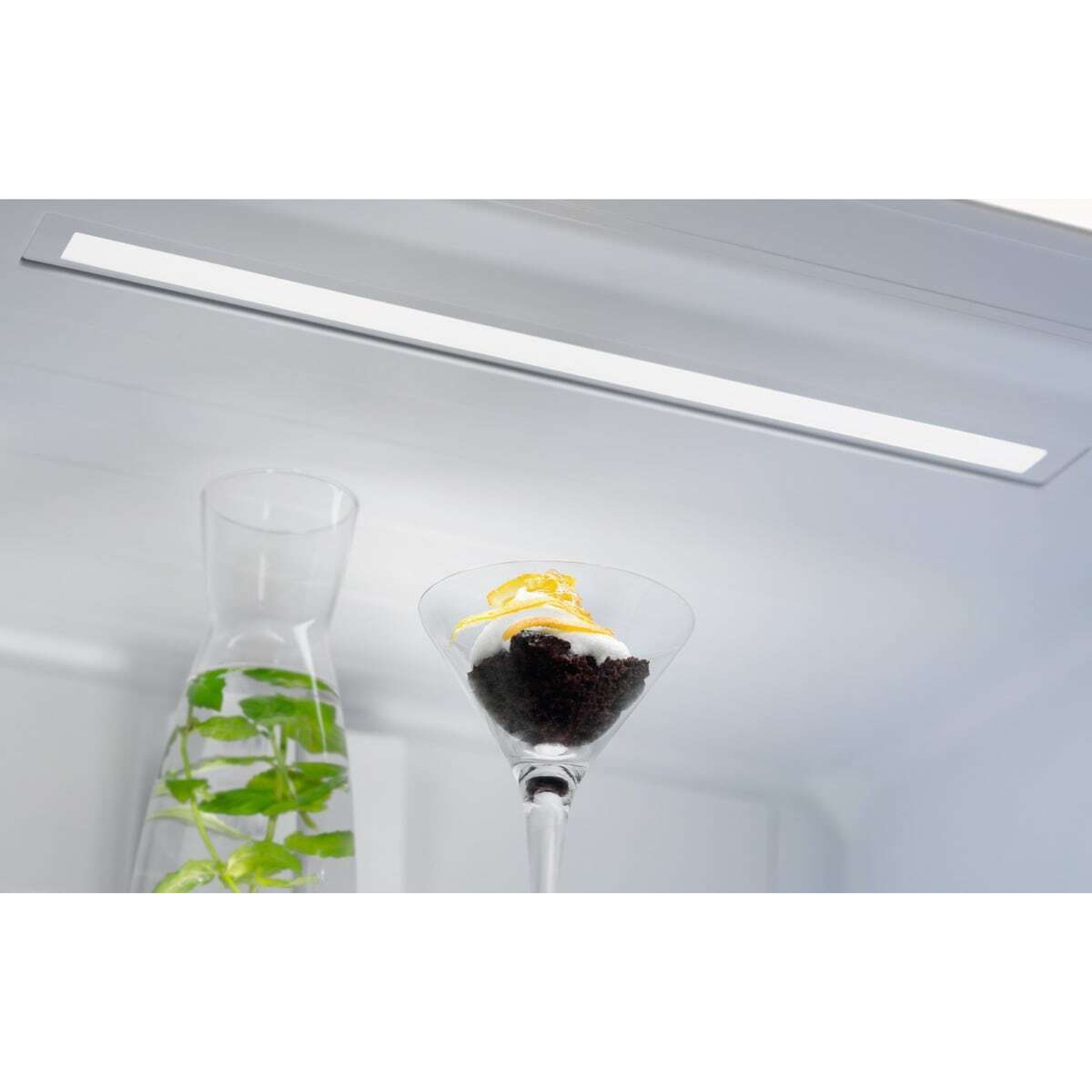 Una caraffa di vetro con foglie di menta in acqua e un dessert in un bicchiere da martini.