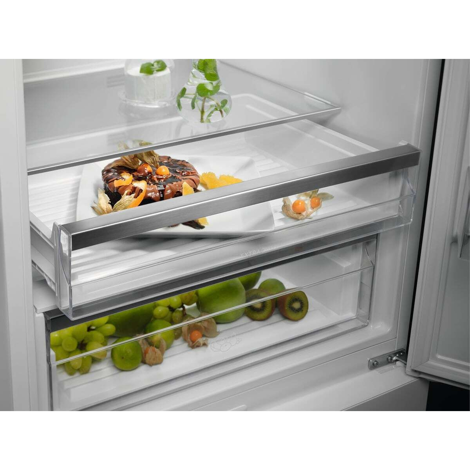 All'interno di un frigorifero: un dolce al cioccolato su un piatto e frutta nei cassetti.