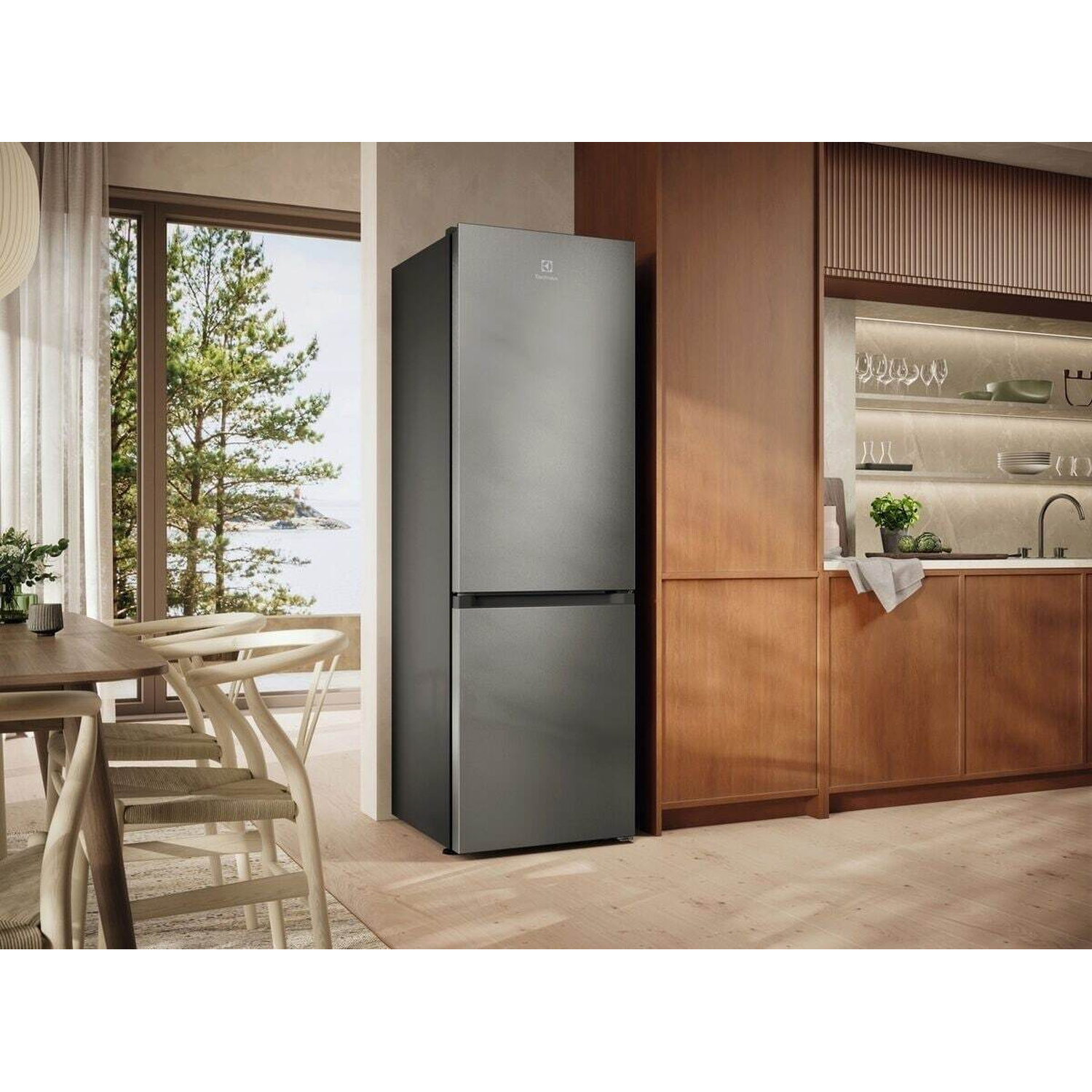 Un frigorifero grigio moderno in una cucina luminosa con mobili in legno e grande finestra.