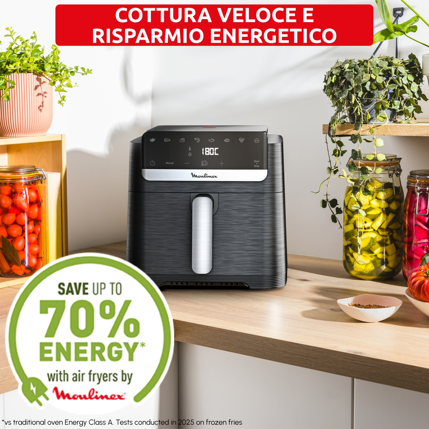 Una friggitrice ad aria Moulinex nera su un piano di lavoro con barattoli di verdure sottaceto.
