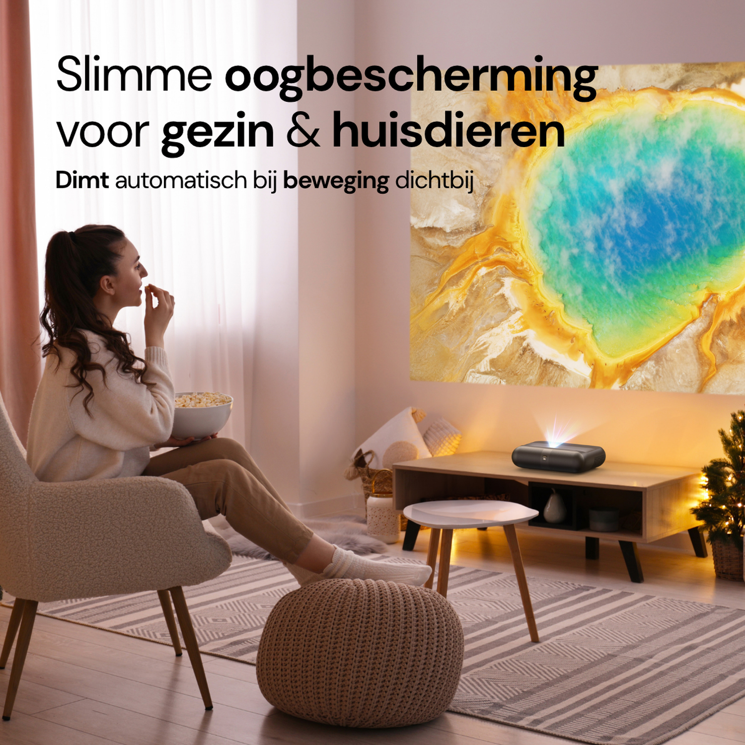 A woman sits in a chair eating popcorn as a projector displays an image onto the wall.