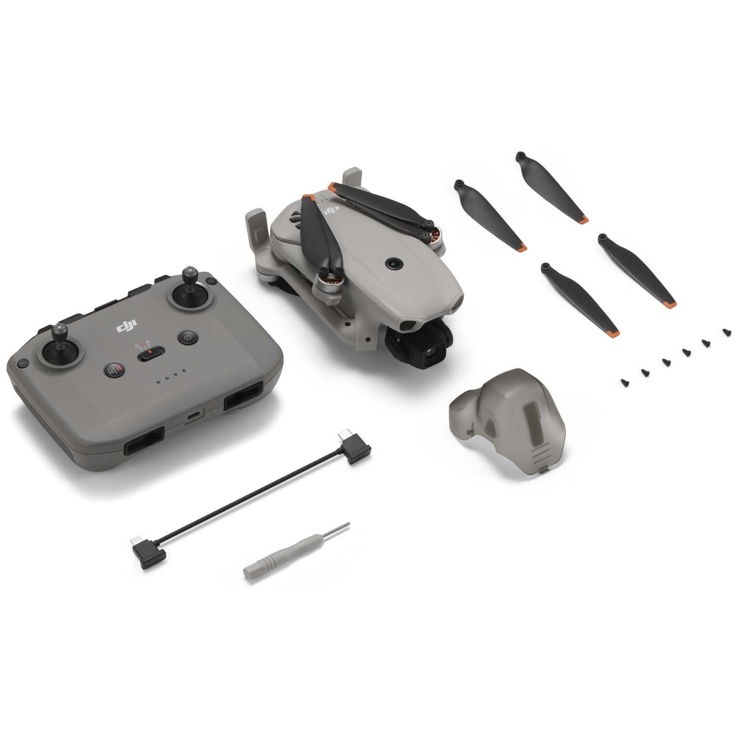 Gray drone, remote, spare propellers, screws, cable, and tool on white background.