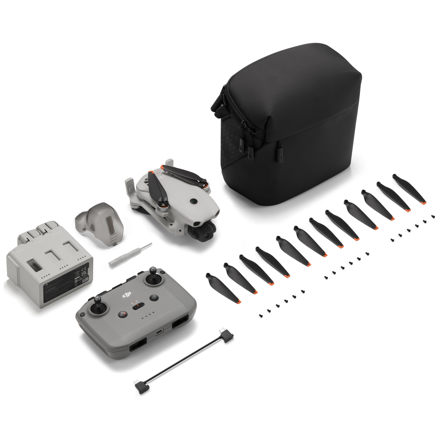 Drone, reservepropellers, batterij, afstandsbediening, tas en gereedschap op wit.