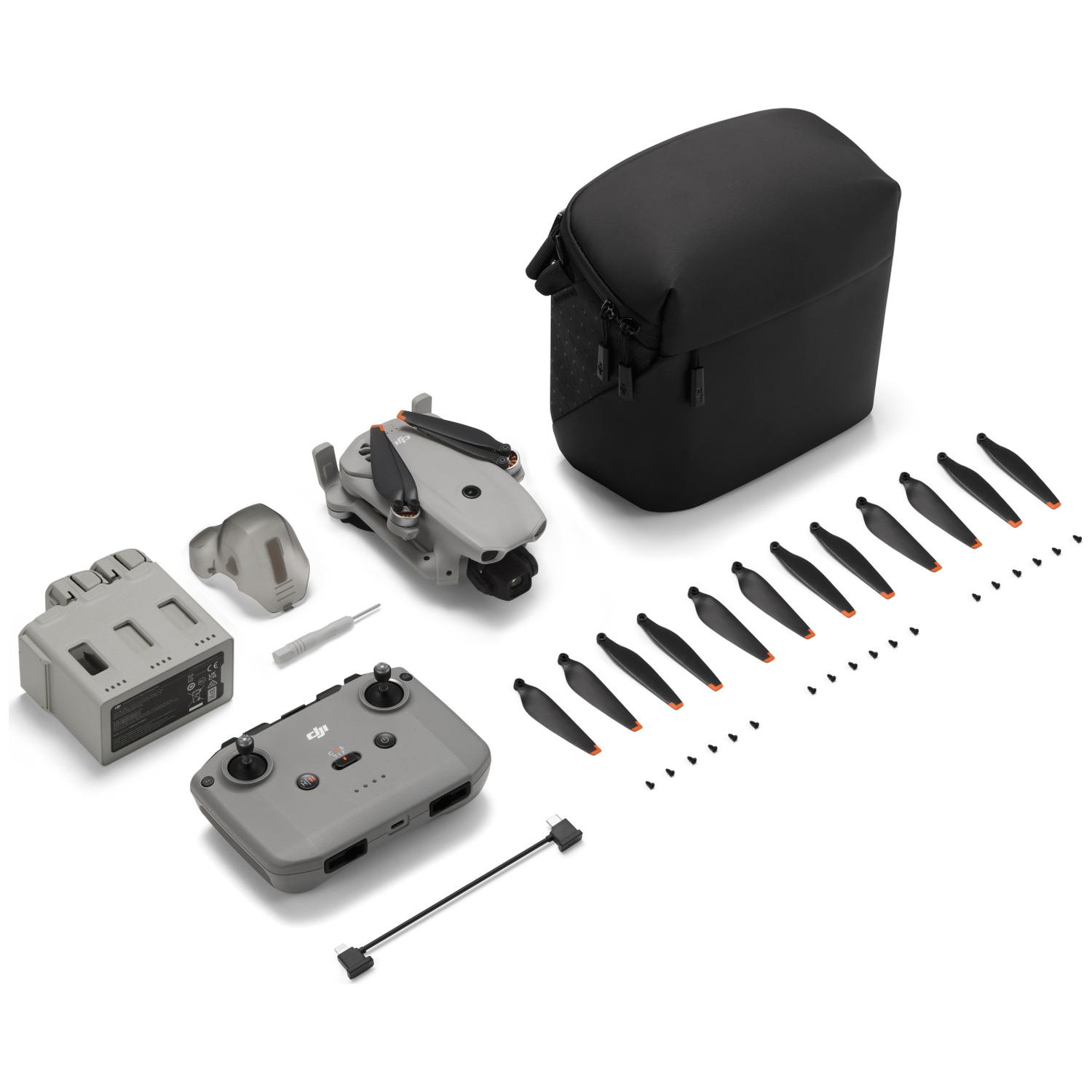 Dronkit met reserveonderdelen, controller, accu en tas op witte achtergrond.