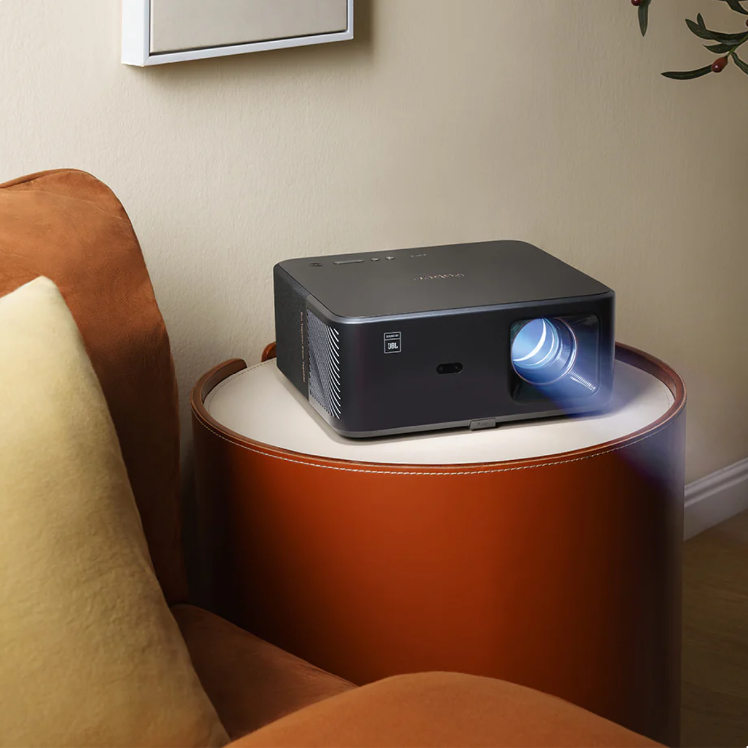 A black projector with a bright blue light beams from its lens, sitting on a round table.