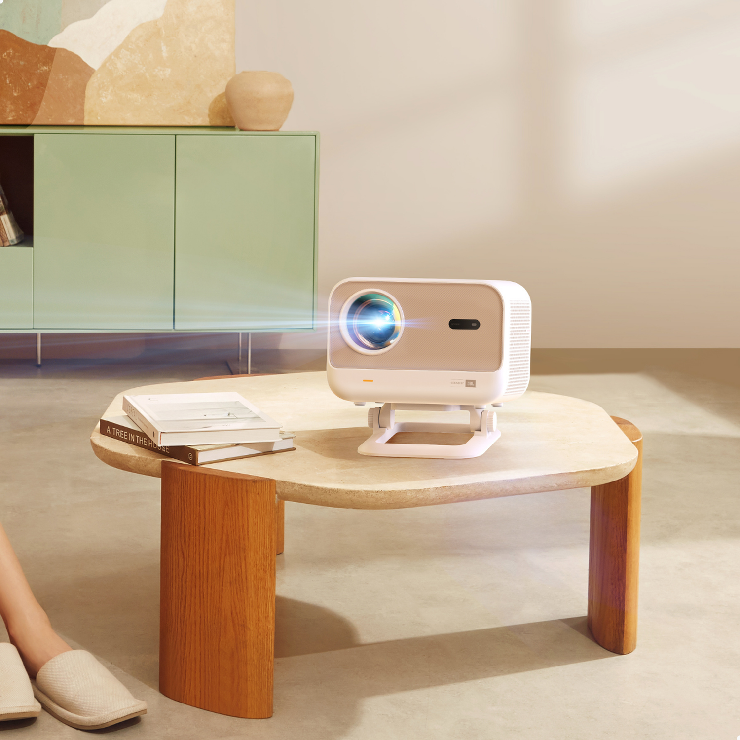 Een witte projector staat op tafel met boeken. Een groene kast staat erachter.