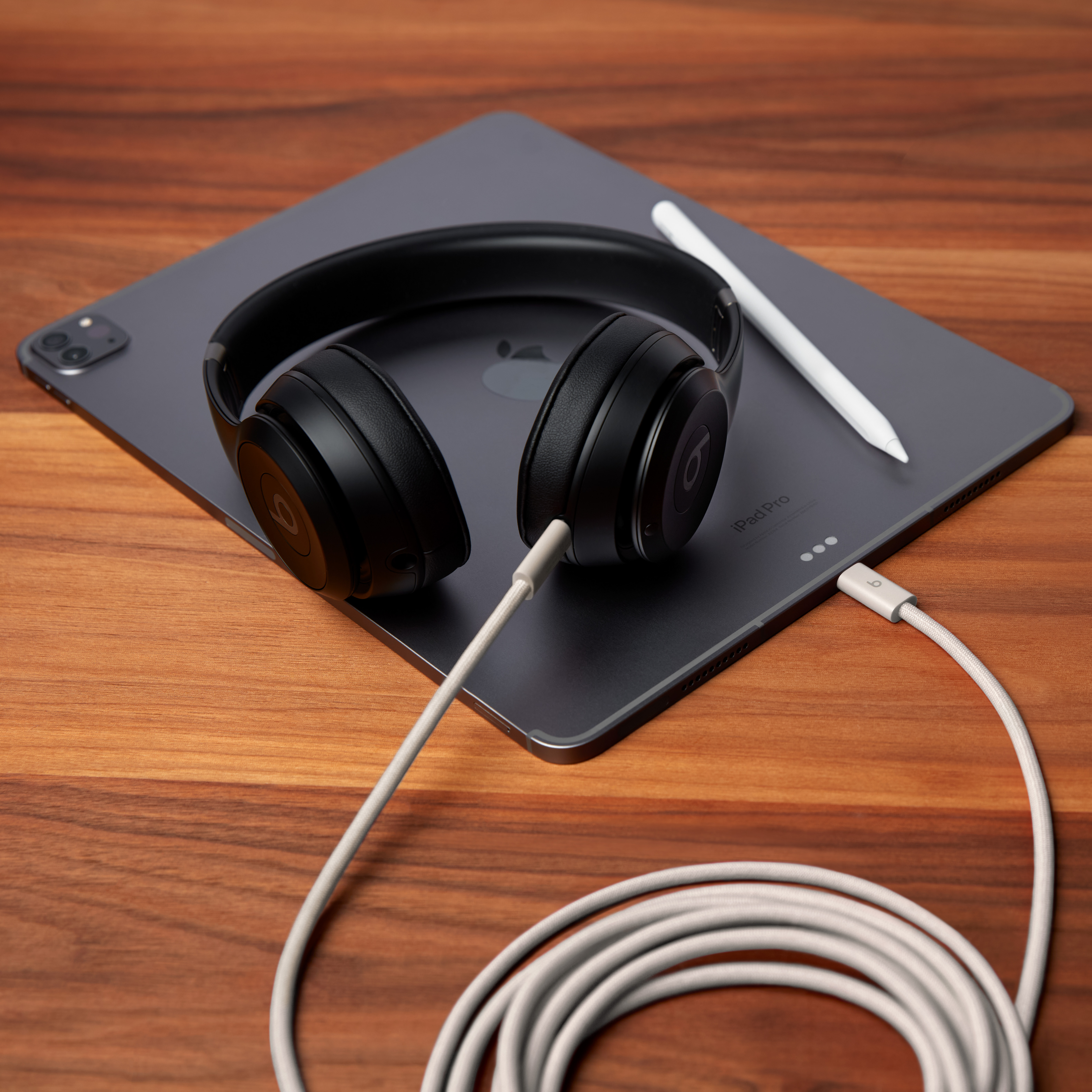 Casque Beats noir et Apple Pencil blanc sur un iPad Pro sombre.