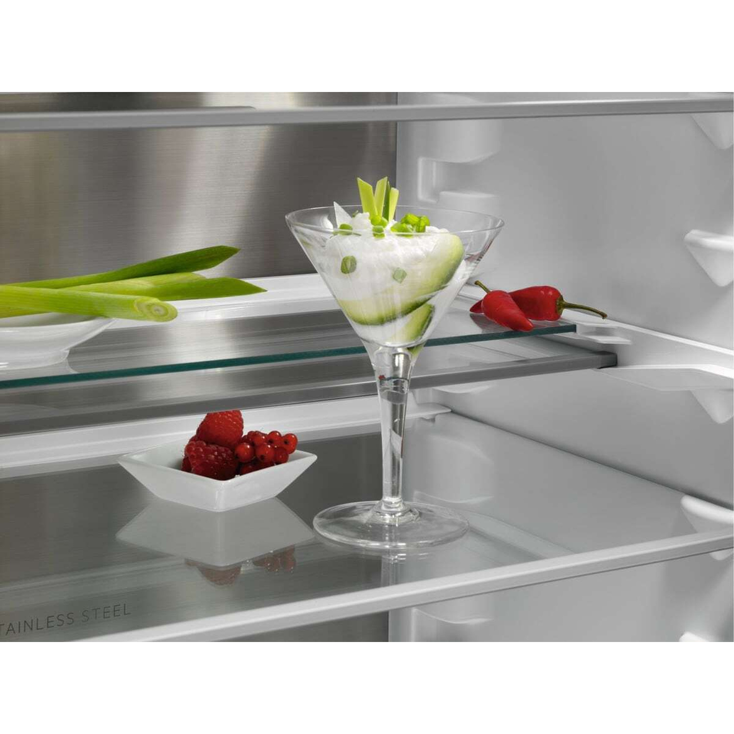 Un dessert in bicchiere con bacche e cipollotti, più peperoncini e cipollotti vicini.