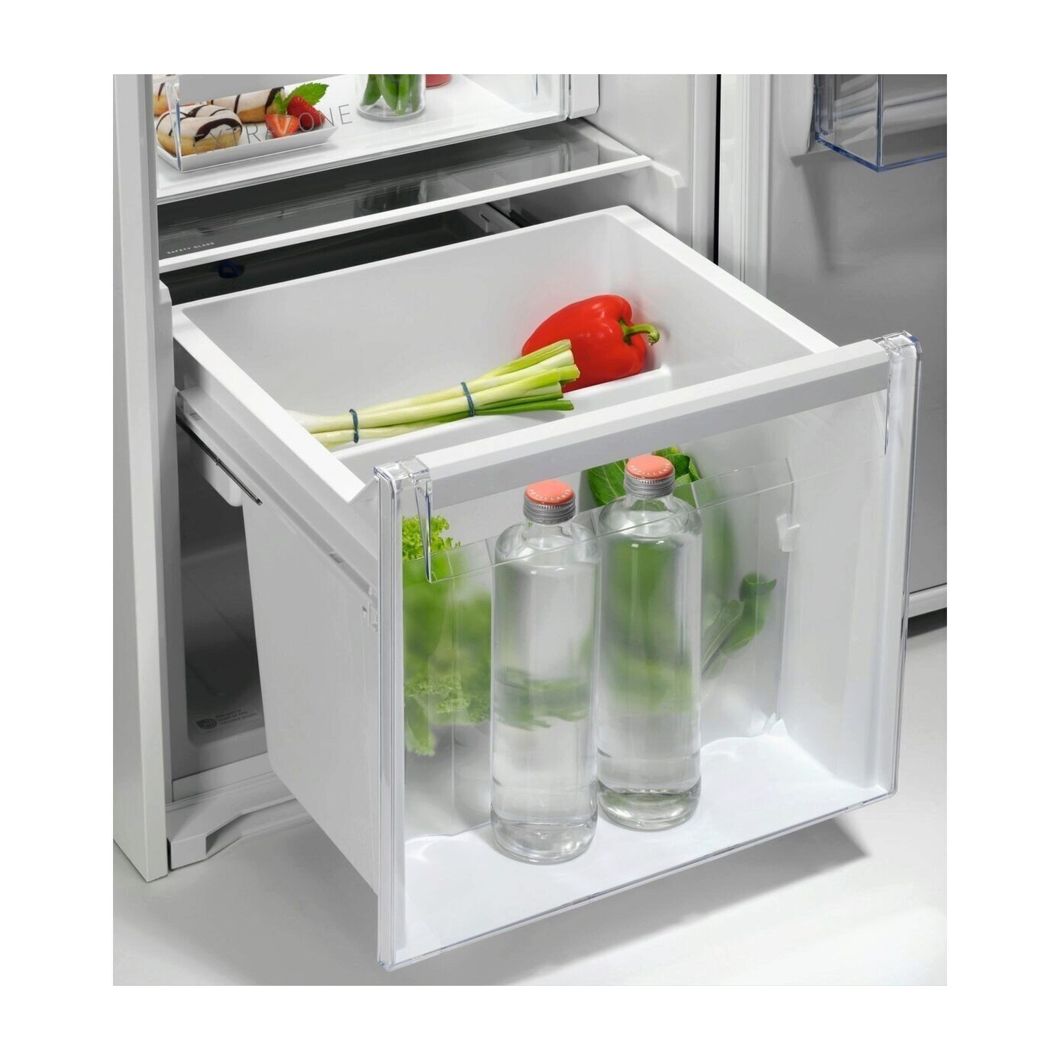 Un cassetto aperto del frigorifero con verdure e bottiglie d'acqua.
