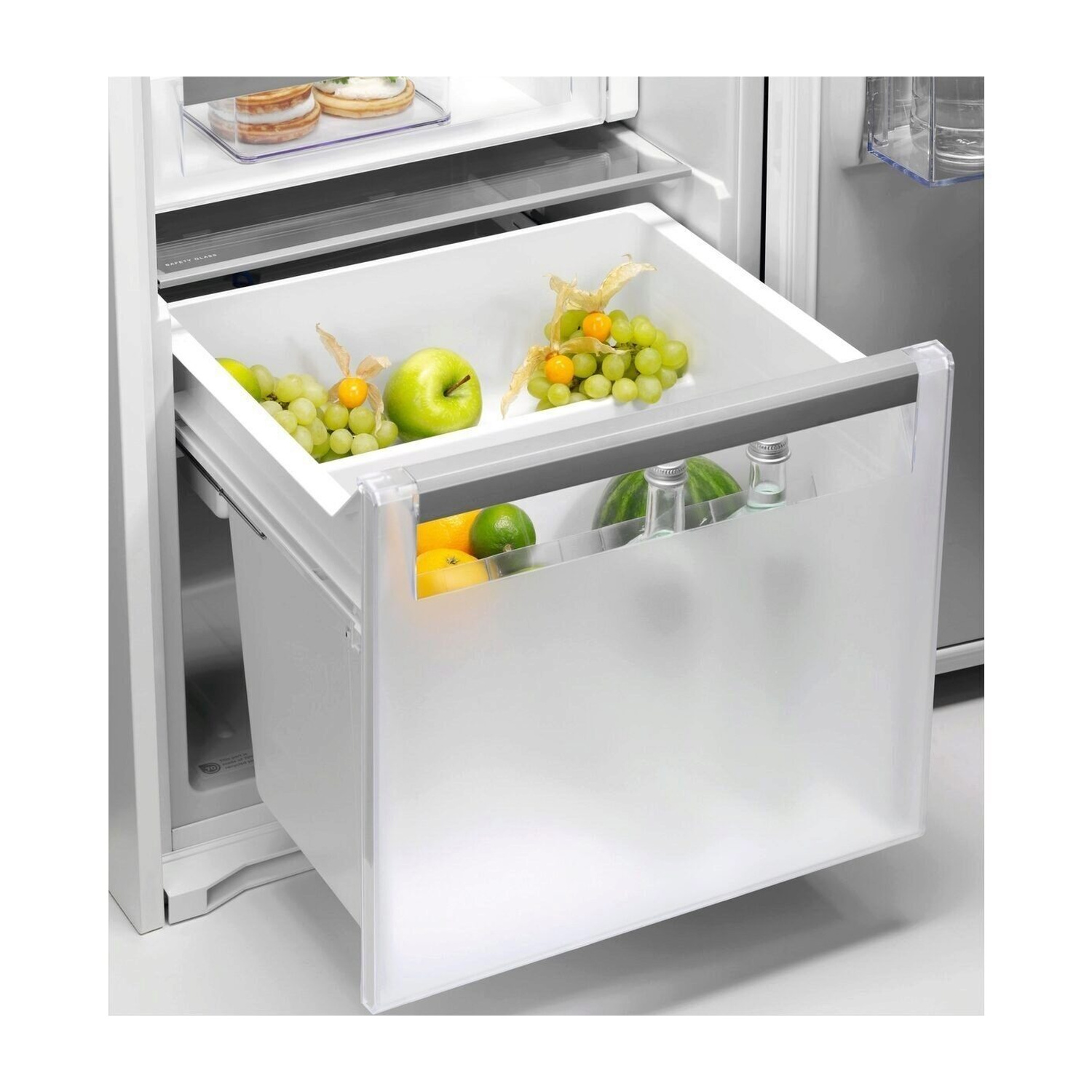 Cassetto frigorifero aperto con frutta: uva, mela, limone, lime, anguria, bottiglie.