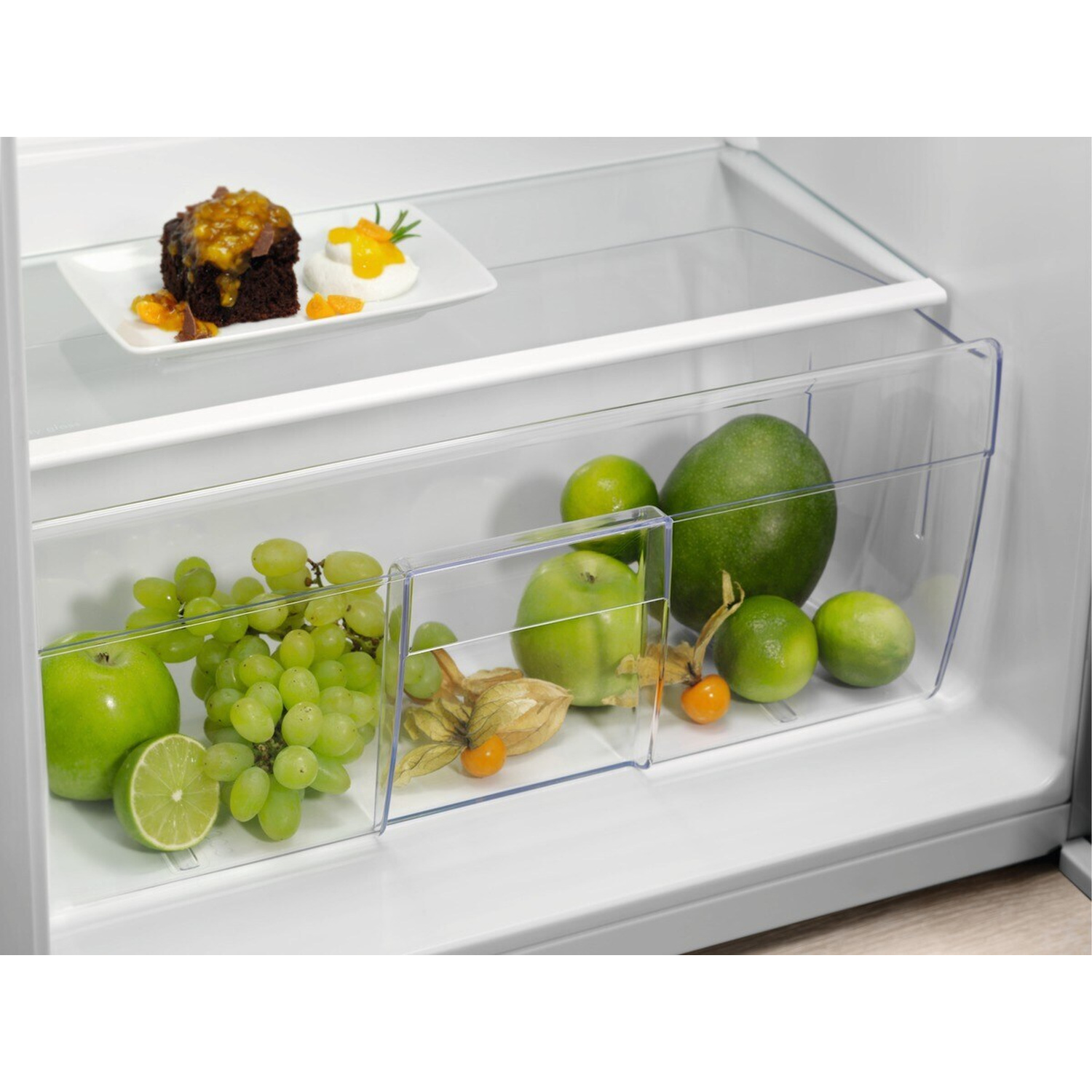 Frutta e torta in frigo: mele verdi, uva, lime, mango, physalis e torta al cioccolato.