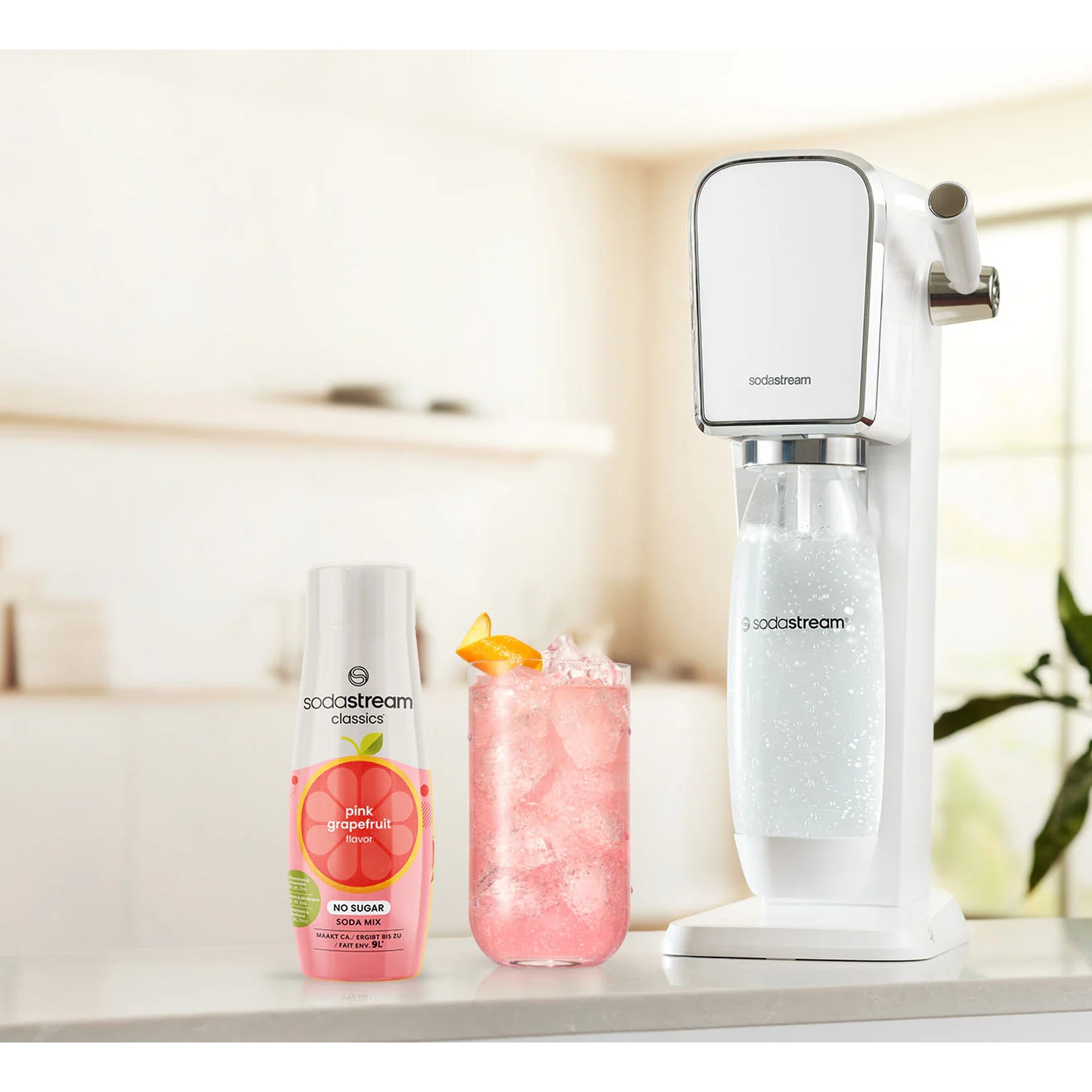 Une machine SodaStream avec une bouteille de sirop de pamplemousse rose et un verre de boisson rose.