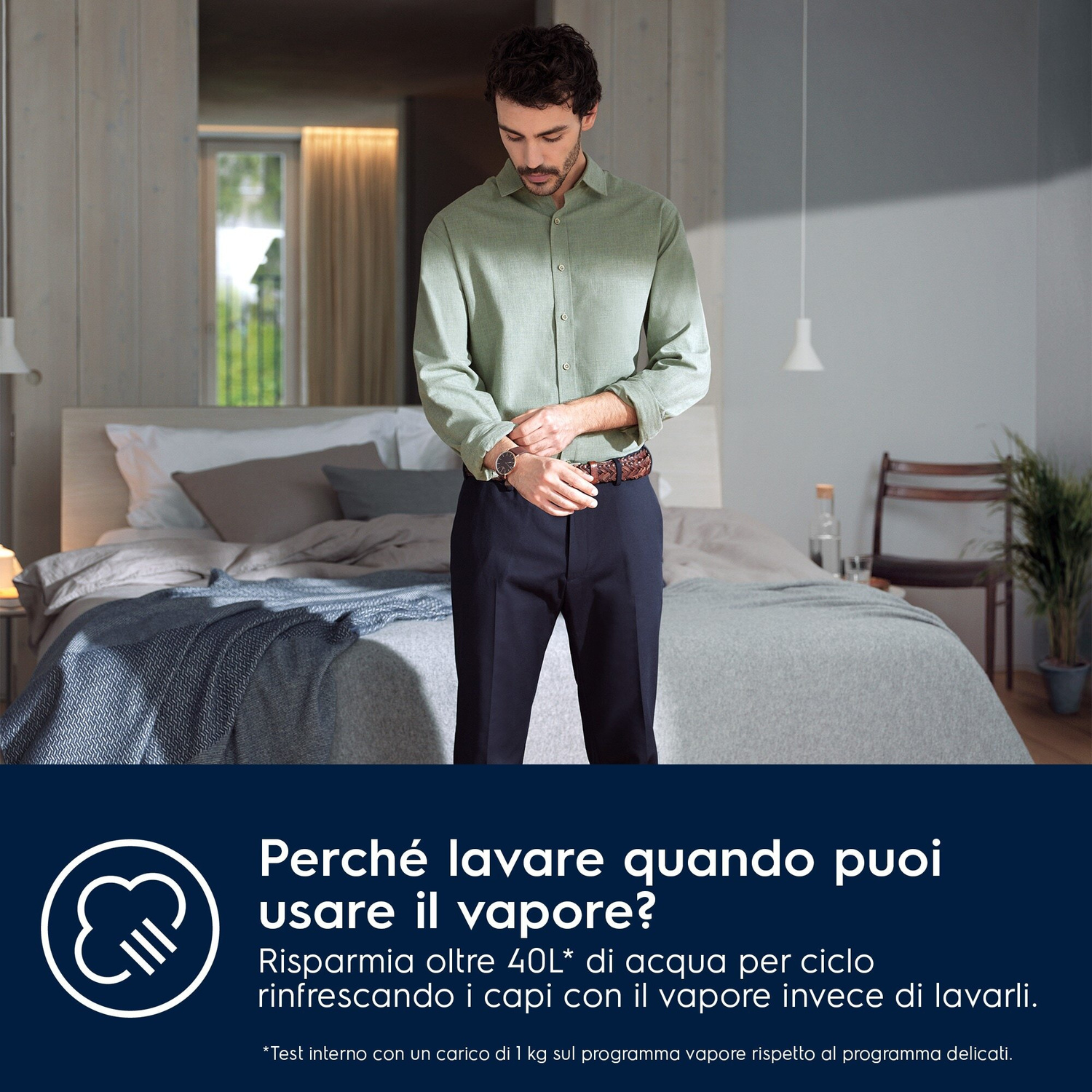 Un uomo con camicia verde e pantaloni scuri si aggiusta l'orologio in una camera.