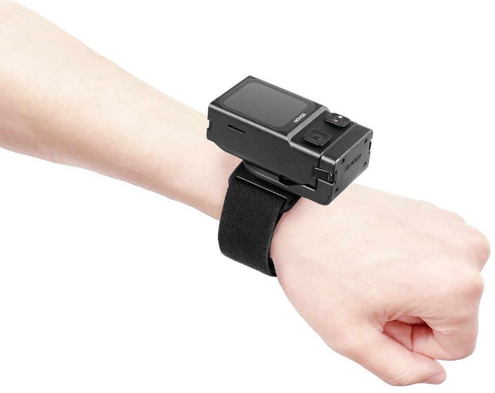 Ein schwarzer tragbarer Scanner ist mit einem schwarzen Riemen am Handgelenk einer Person befestigt.