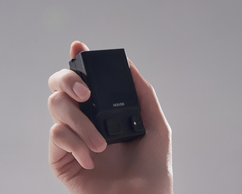 Eine Hand hält ein kleines schwarzes elektronisches Gerät mit der Aufschrift "HOVER".