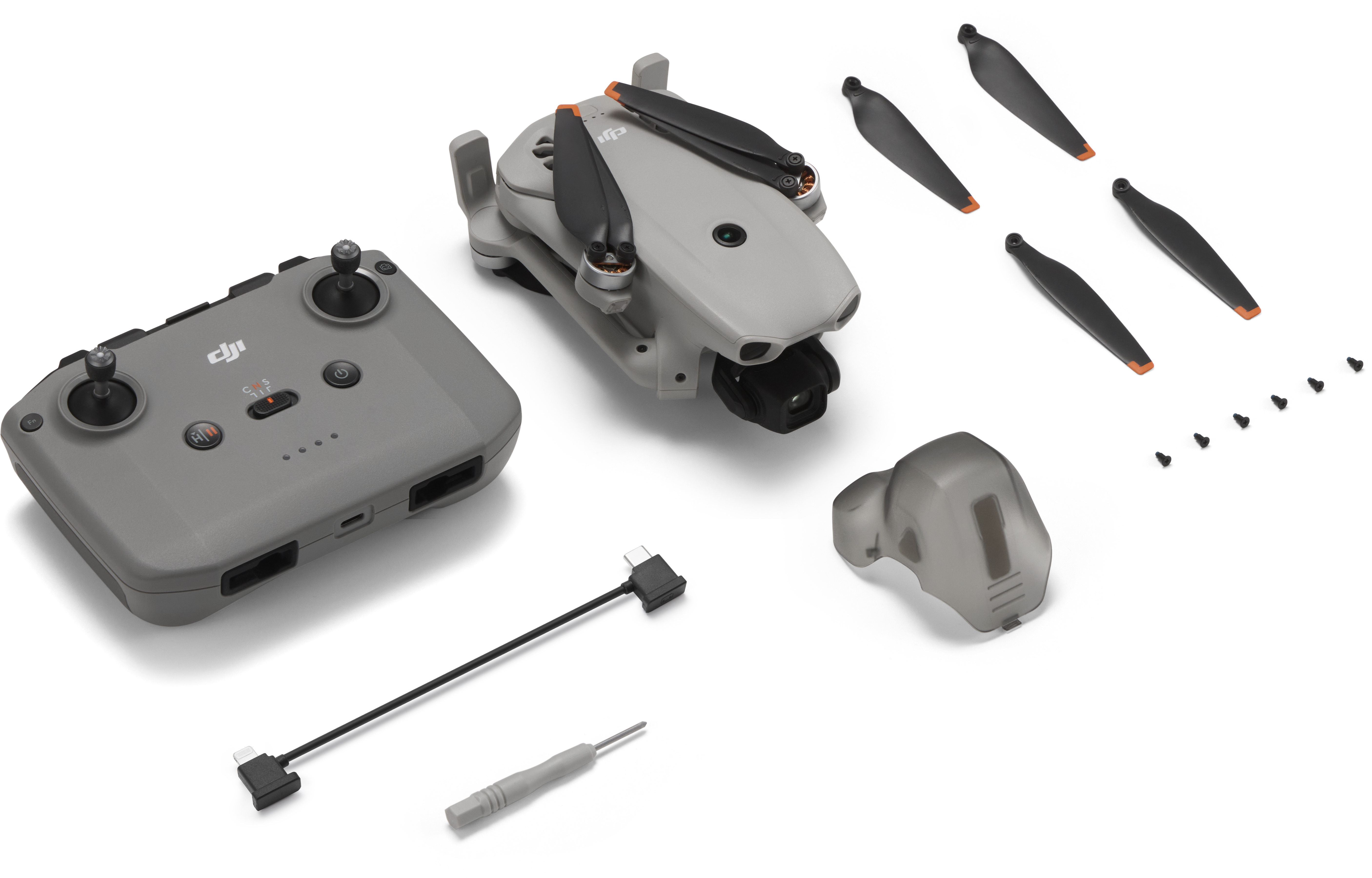 Eine graue Drohne, ein Controller, Propeller, Kabel und Schrauben auf weißem Hintergrund.