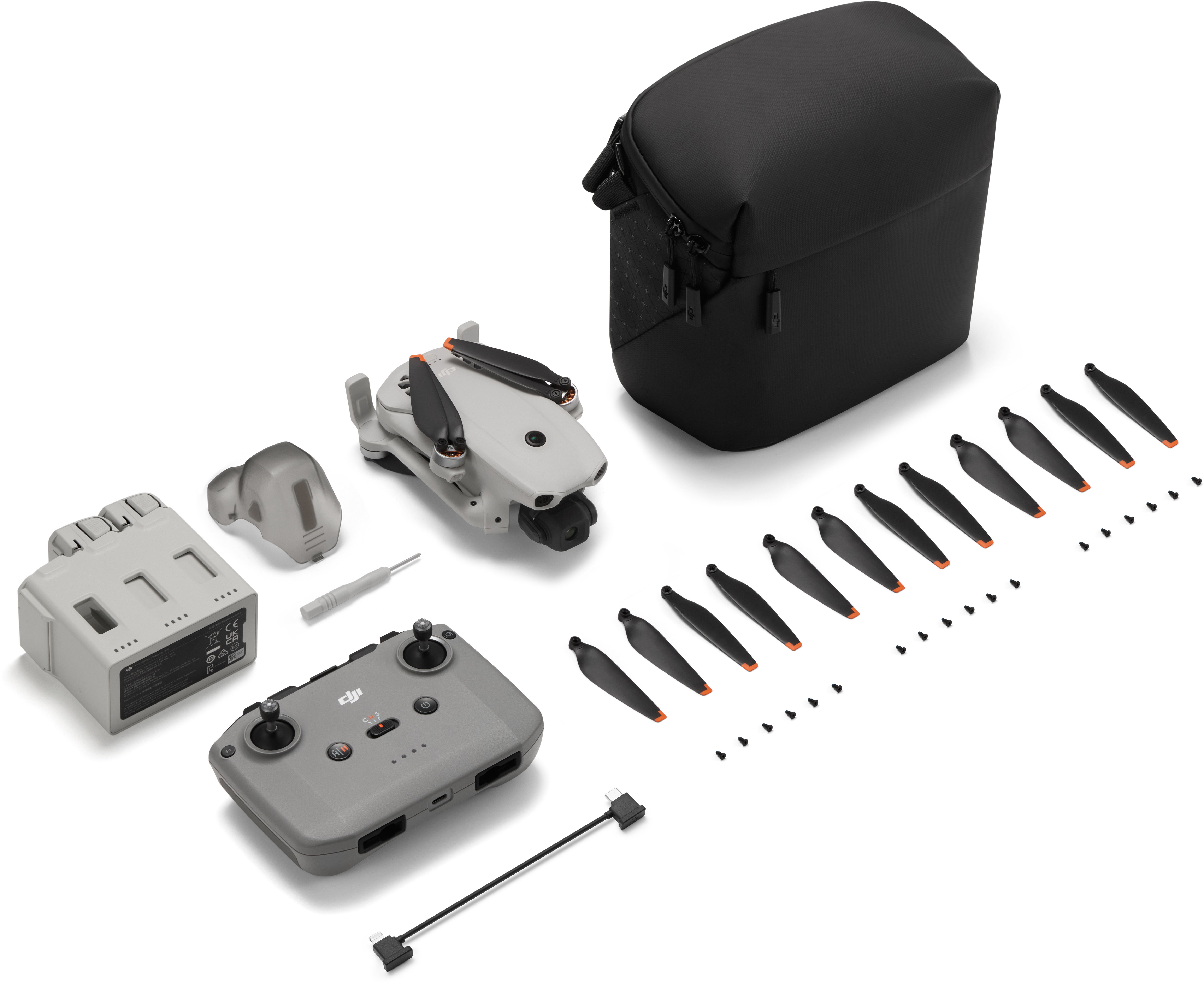 Un kit drone grigio chiaro con telecomando, batteria, eliche e custodia.