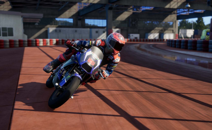 Un corredor de motos con equipo completo se inclina en una curva en una pista de carreras.