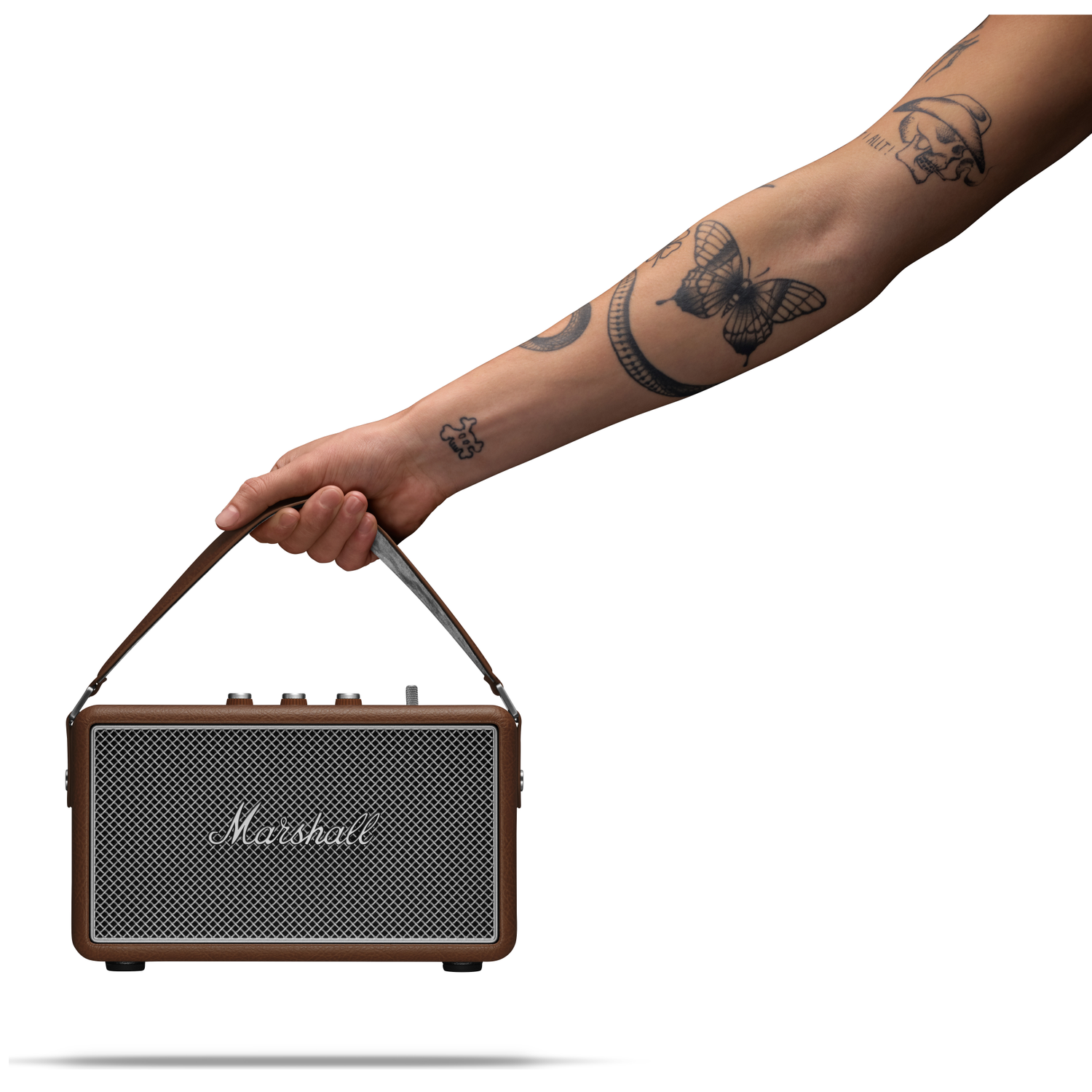 Een getatoeëerde hand houdt een bruine Marshall luidspreker met leren riem vast.
