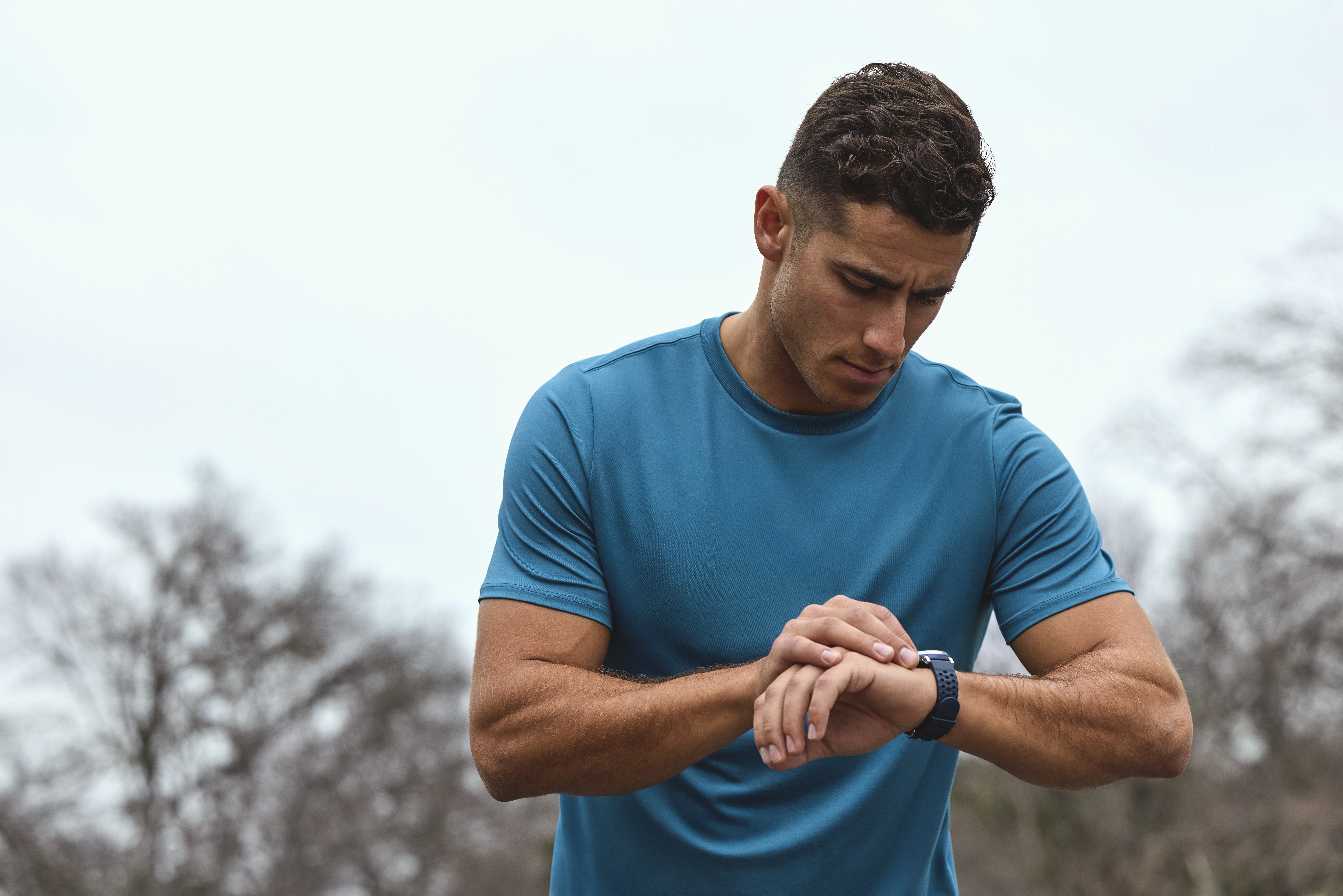 Un homme en t-shirt bleu regarde sa montre connectée.