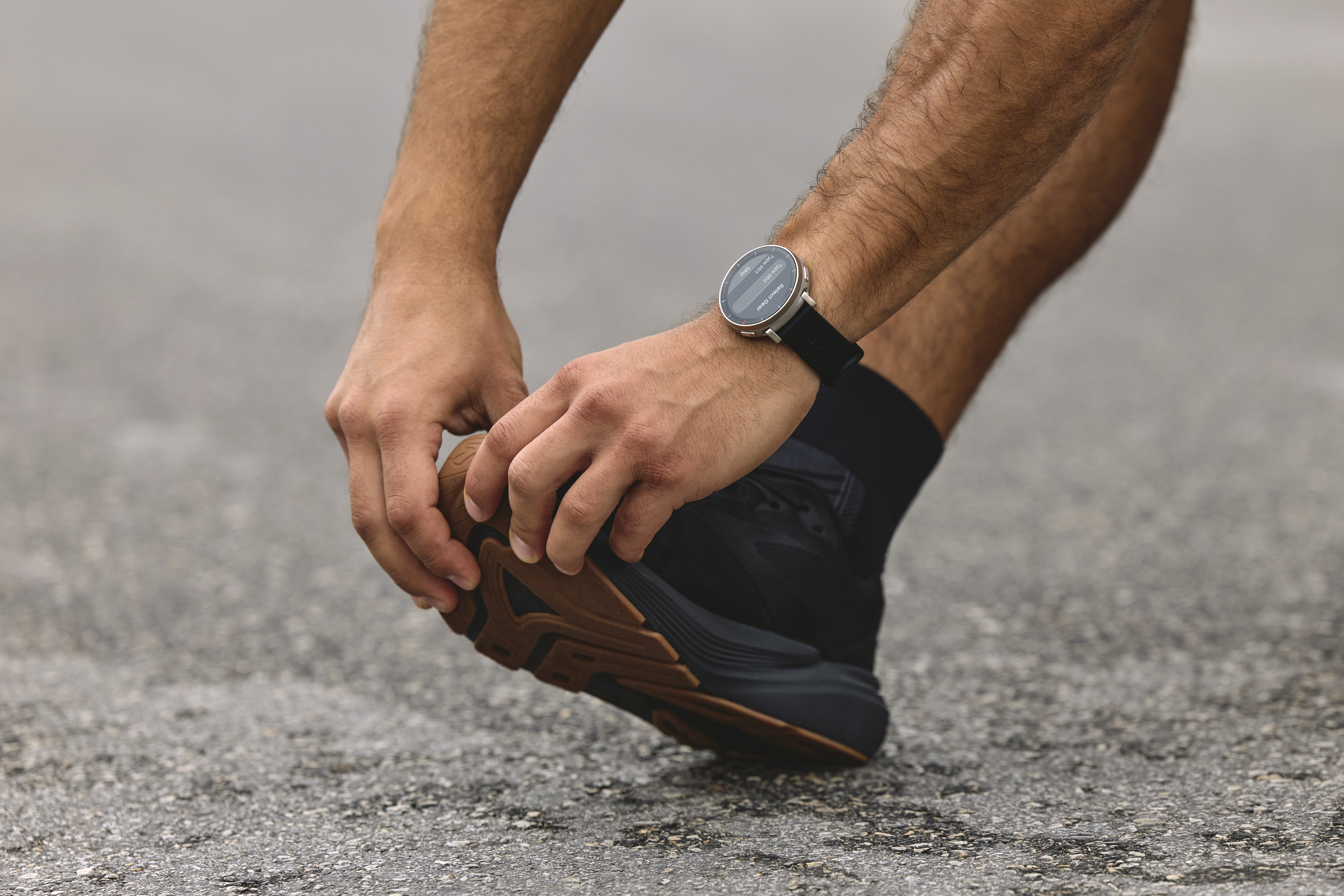 Ein Mann zieht seinen schwarzen Schuh an, mit einer Uhr am Handgelenk.