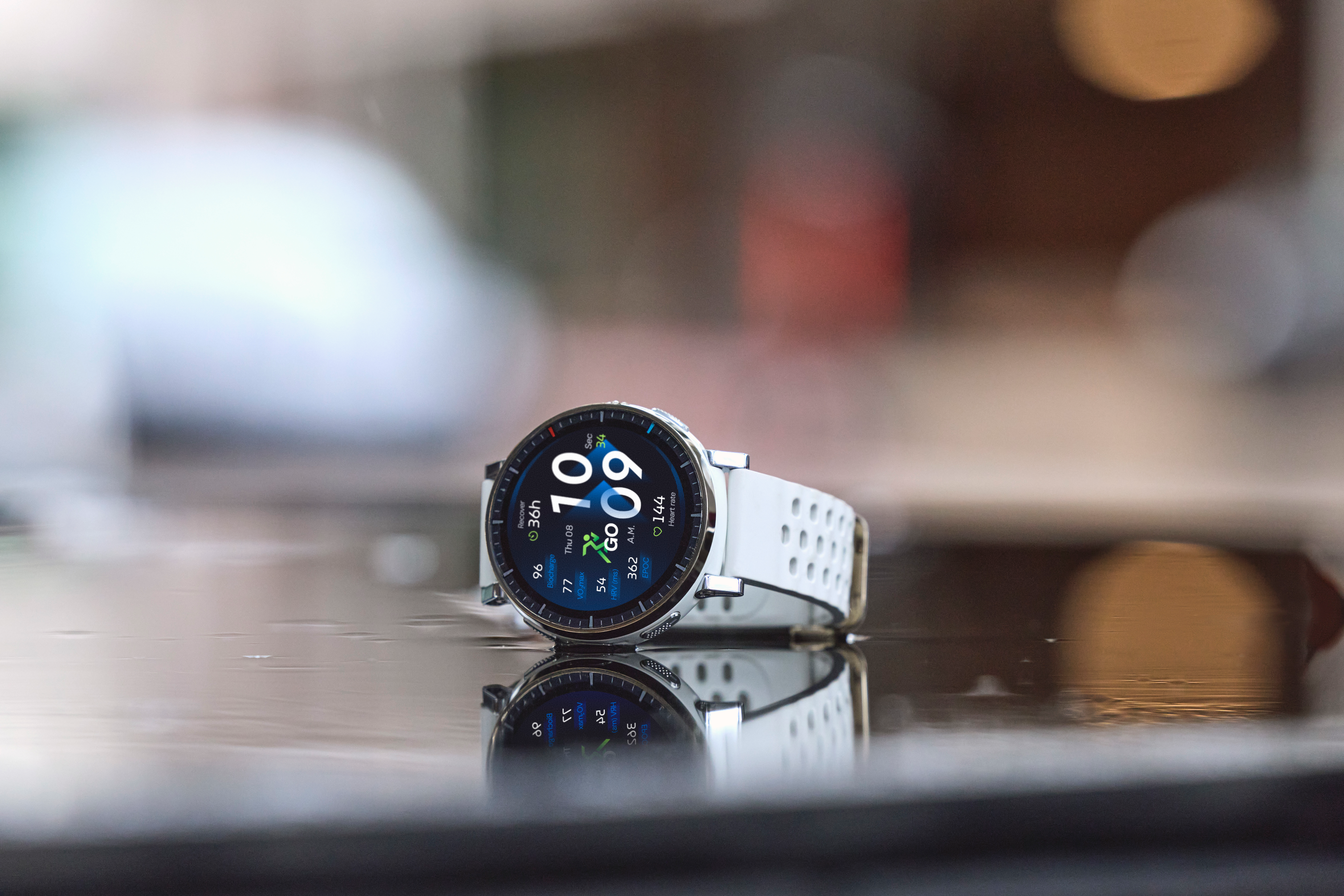 Une montre connectée blanche repose sur une surface humide, son écran affiche l'heure et des données.
