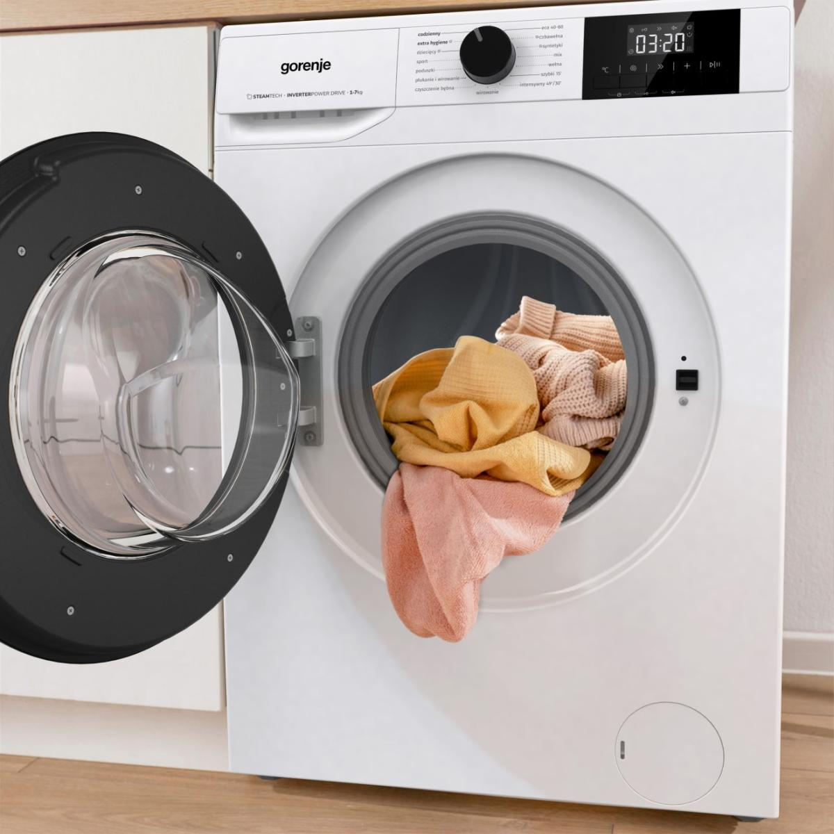 Biała pralka Gorenje z otwartymi drzwiami, w środku kolorowe pranie.
