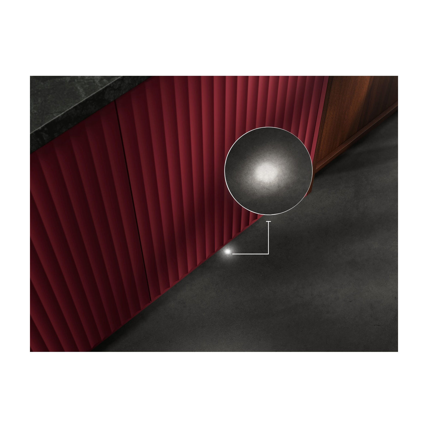 Frontali armadio rossi scanalati e accenti in legno su pavimento scuro con illuminazione.