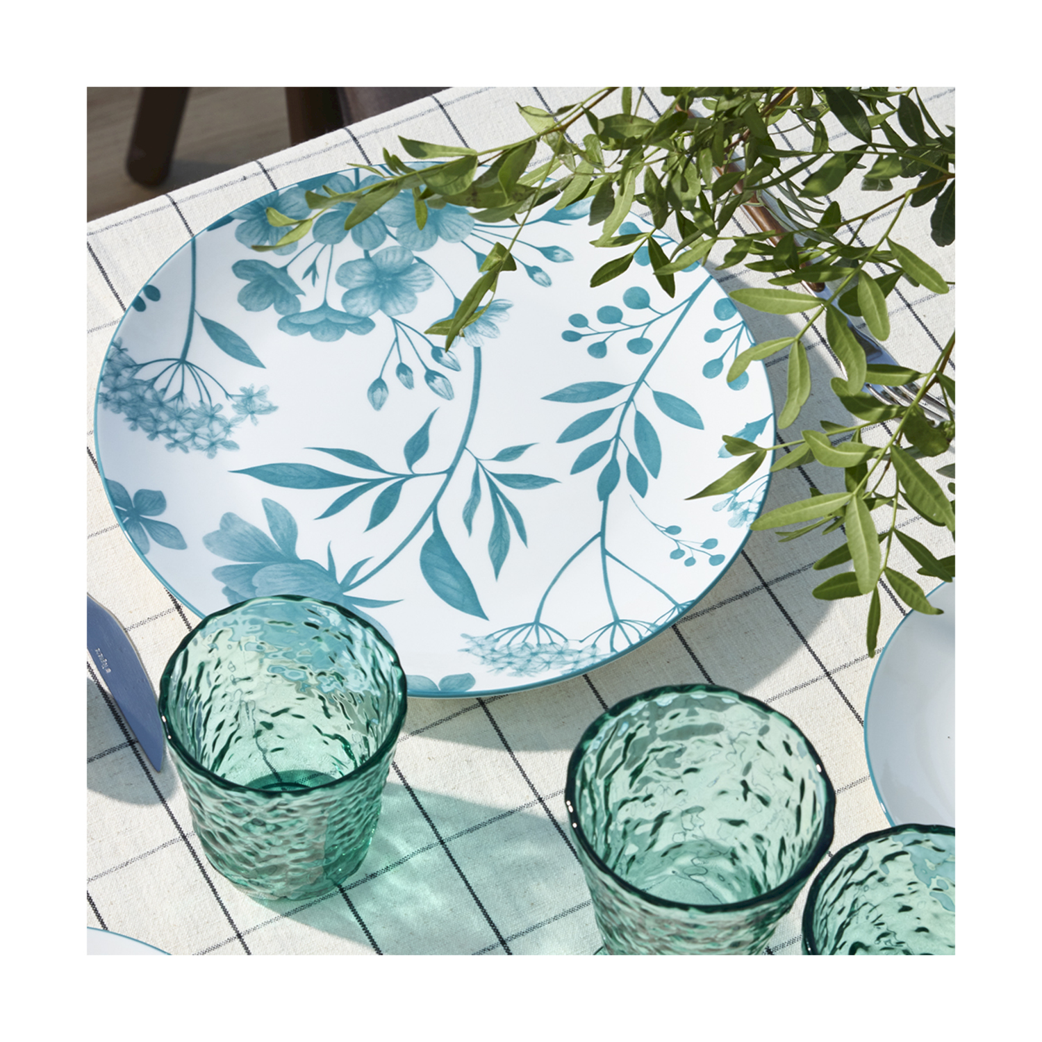 Un piatto bianco con disegno floreale blu su una tovaglia a quadri.