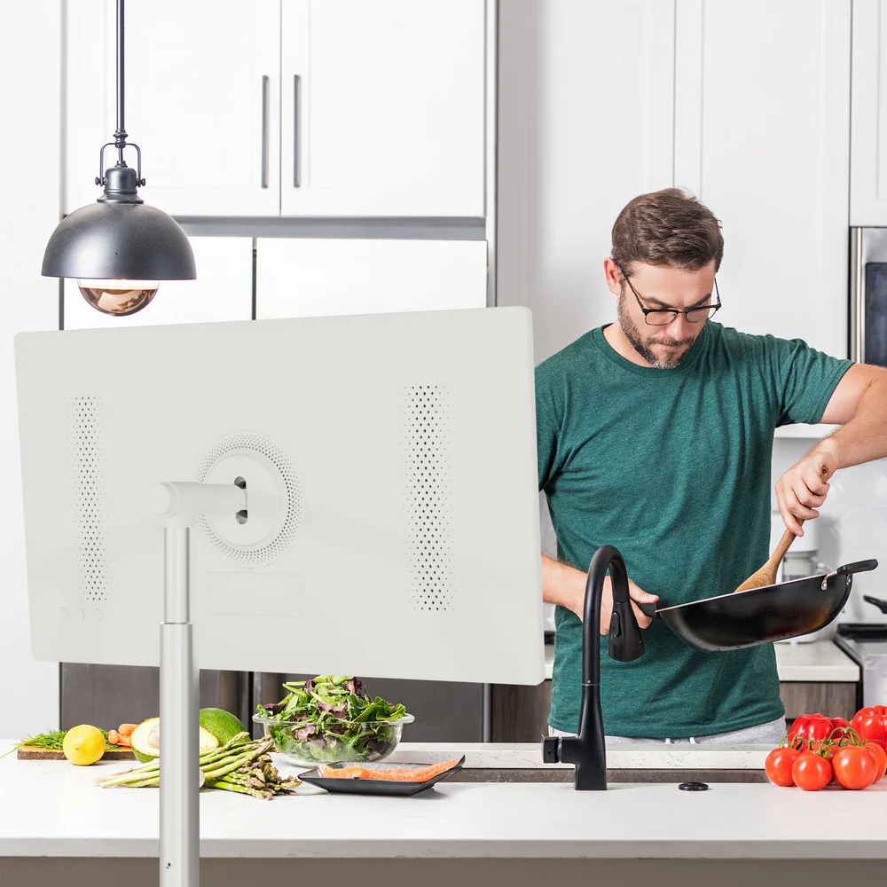Hombre con camisa verde cocina en cocina, con verduras y salmón en encimera.