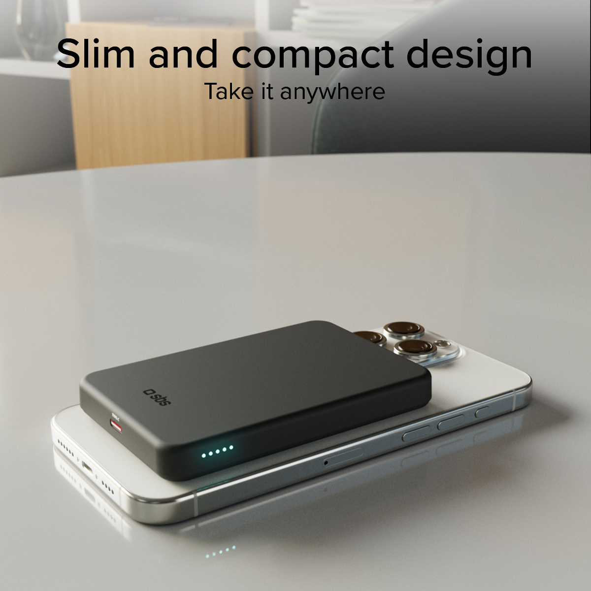 Eine schwarze Powerbank liegt auf einem silbernen Smartphone. Vier blaue Lichter zeigen Ladung an.