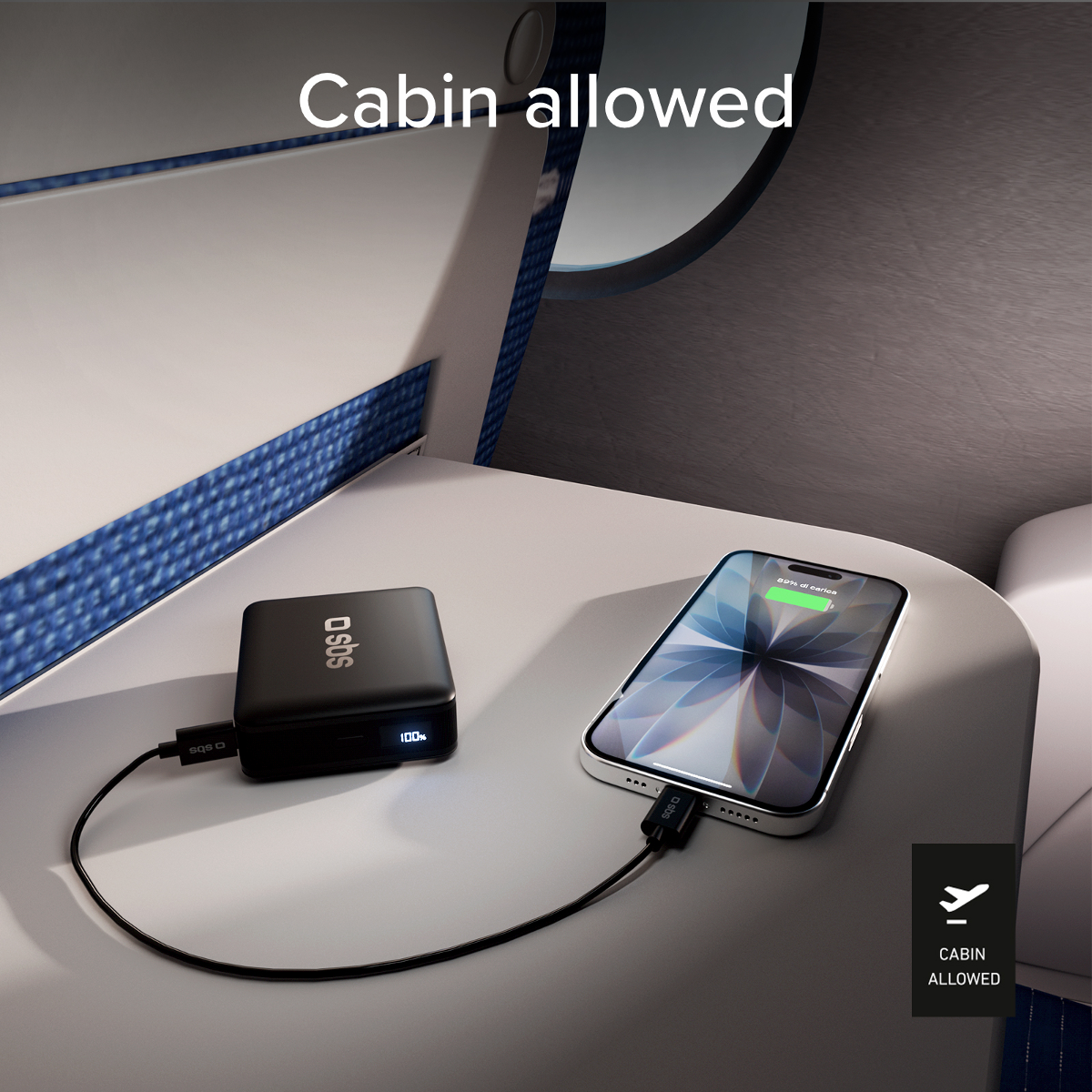 Eine schwarze Powerbank lädt ein Handy auf einem Flugzeugtisch. Kabine erlaubt.