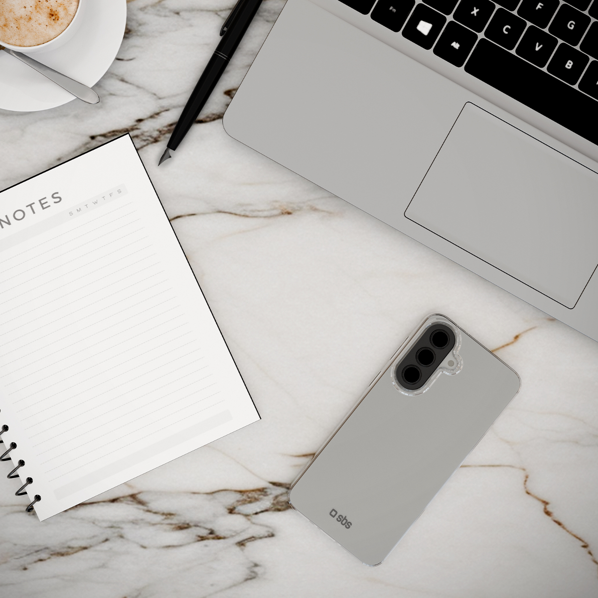 Ein Notizbuch, ein Stift, eine Kaffeetasse und ein Smartphone auf Marmor.