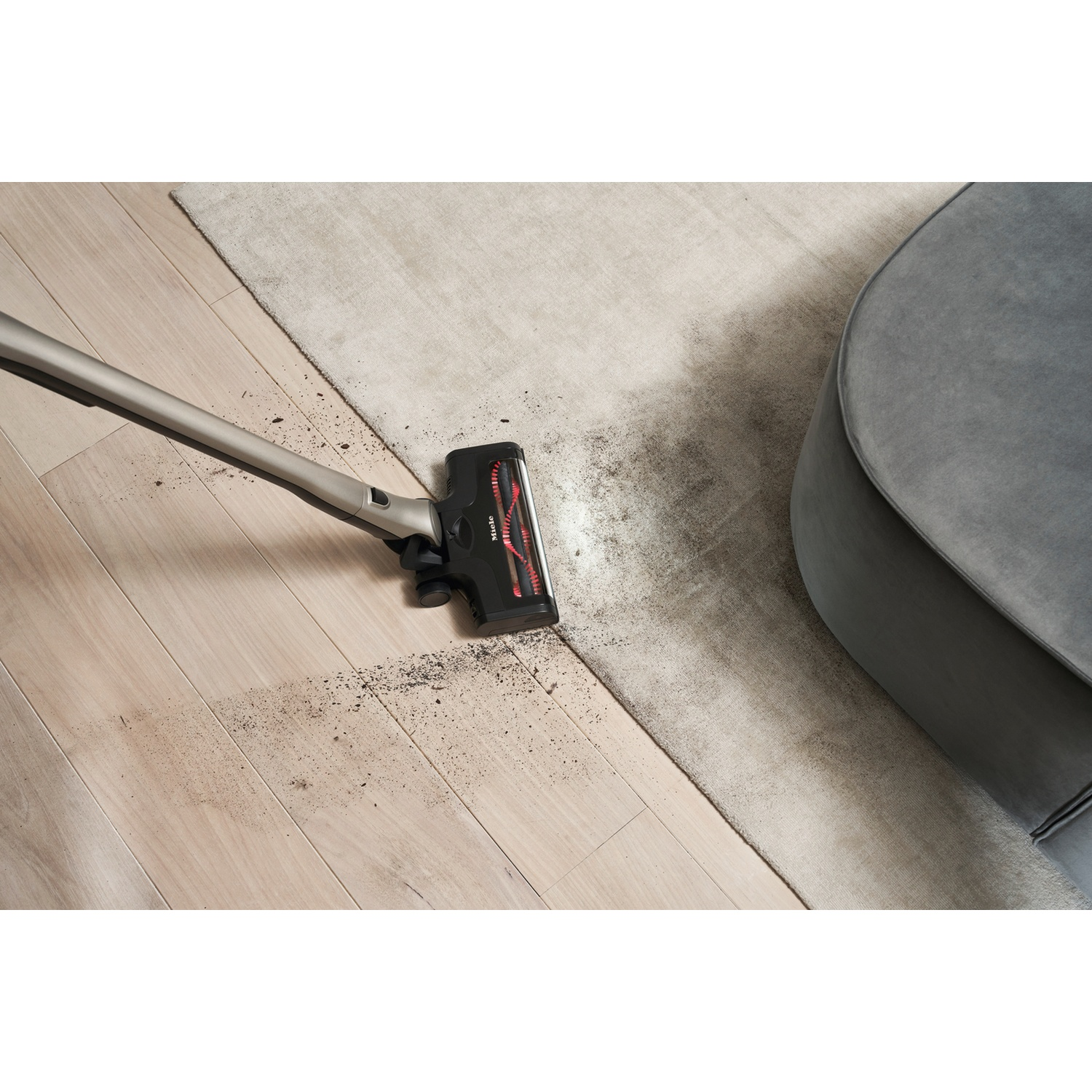 Un aspirateur nettoie la saleté d'un parquet et d'un tapis.