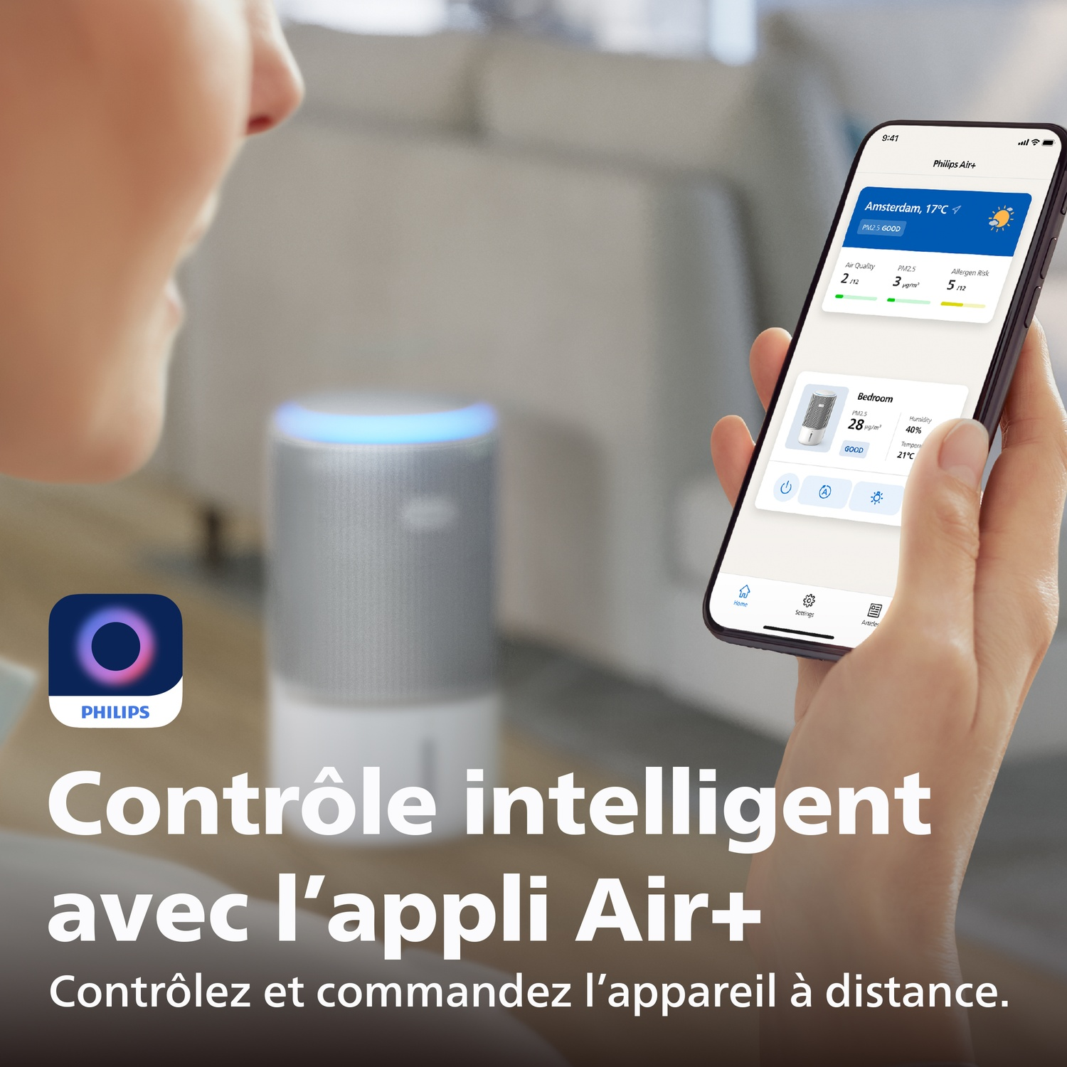 Personne tenant un téléphone avec l'appli Philips Air+, à côté d'un purificateur d'air.