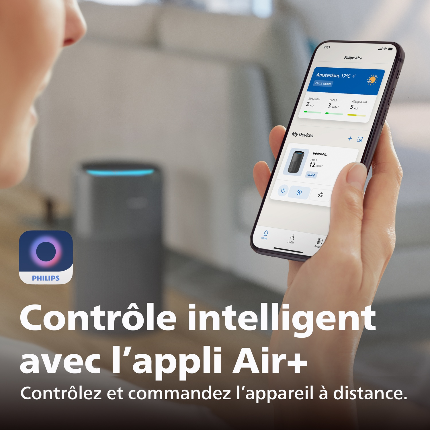 A hand holds a smartphone displaying the Philips Air+ app. An air purifier is visible in the background.