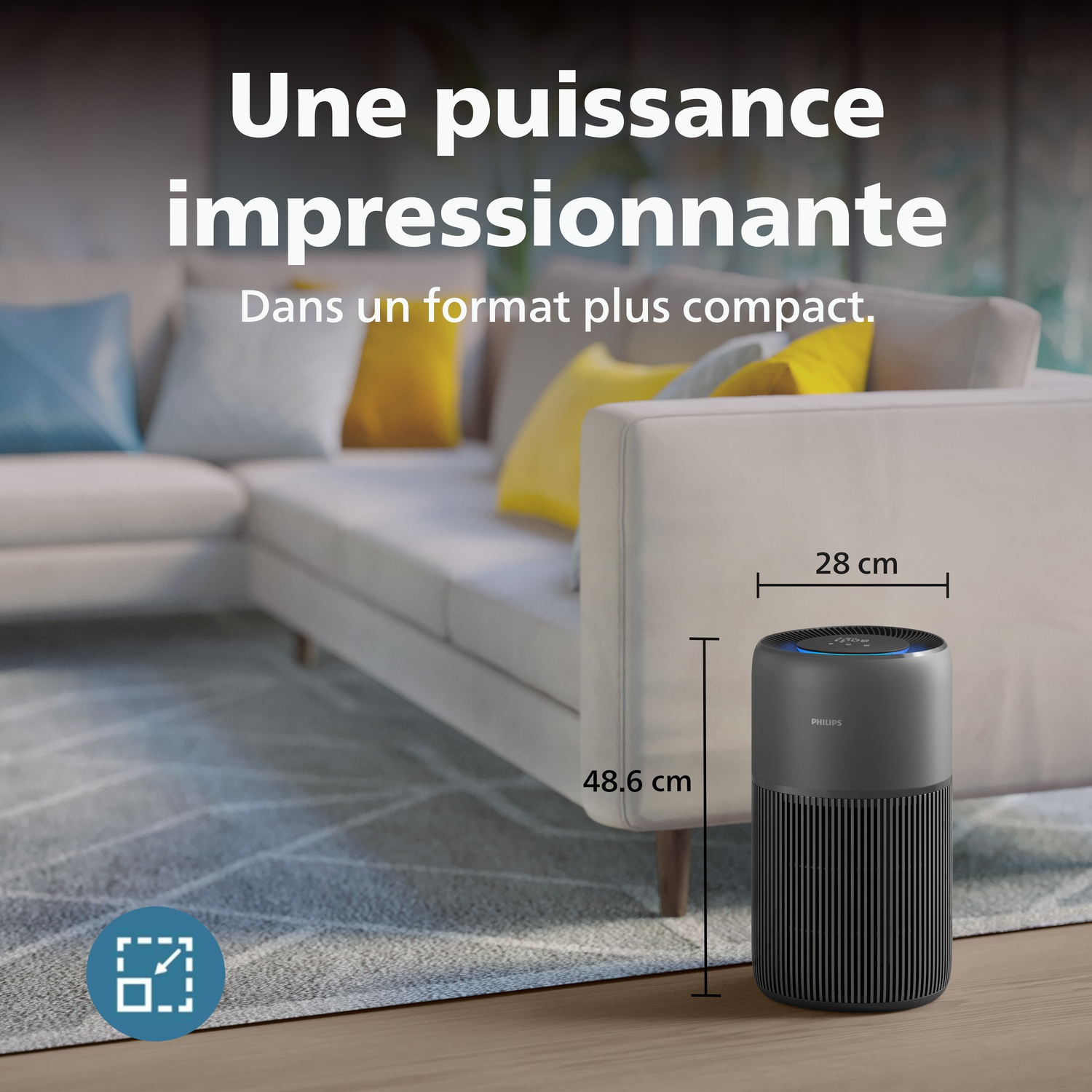 A dark air purifier stands beside a sofa. Dimensions are 28x48.6 cm.