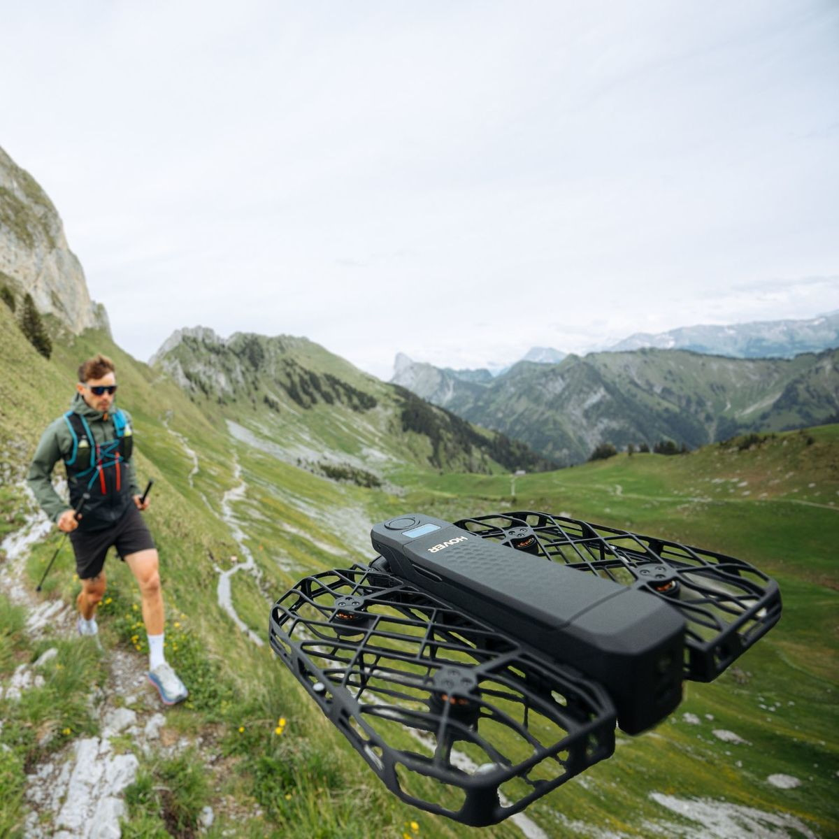 Un uomo corre su un sentiero di montagna, un drone vola in primo piano.