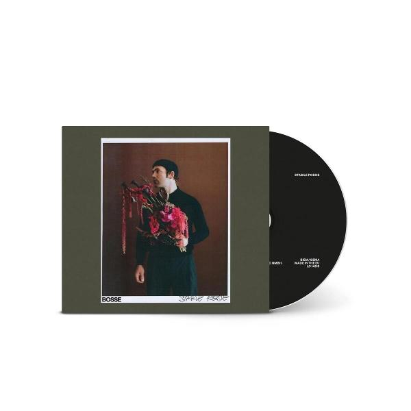 Mann mit Hut hält Blumenstrauß vor CD-Cover mit Bandnamen.