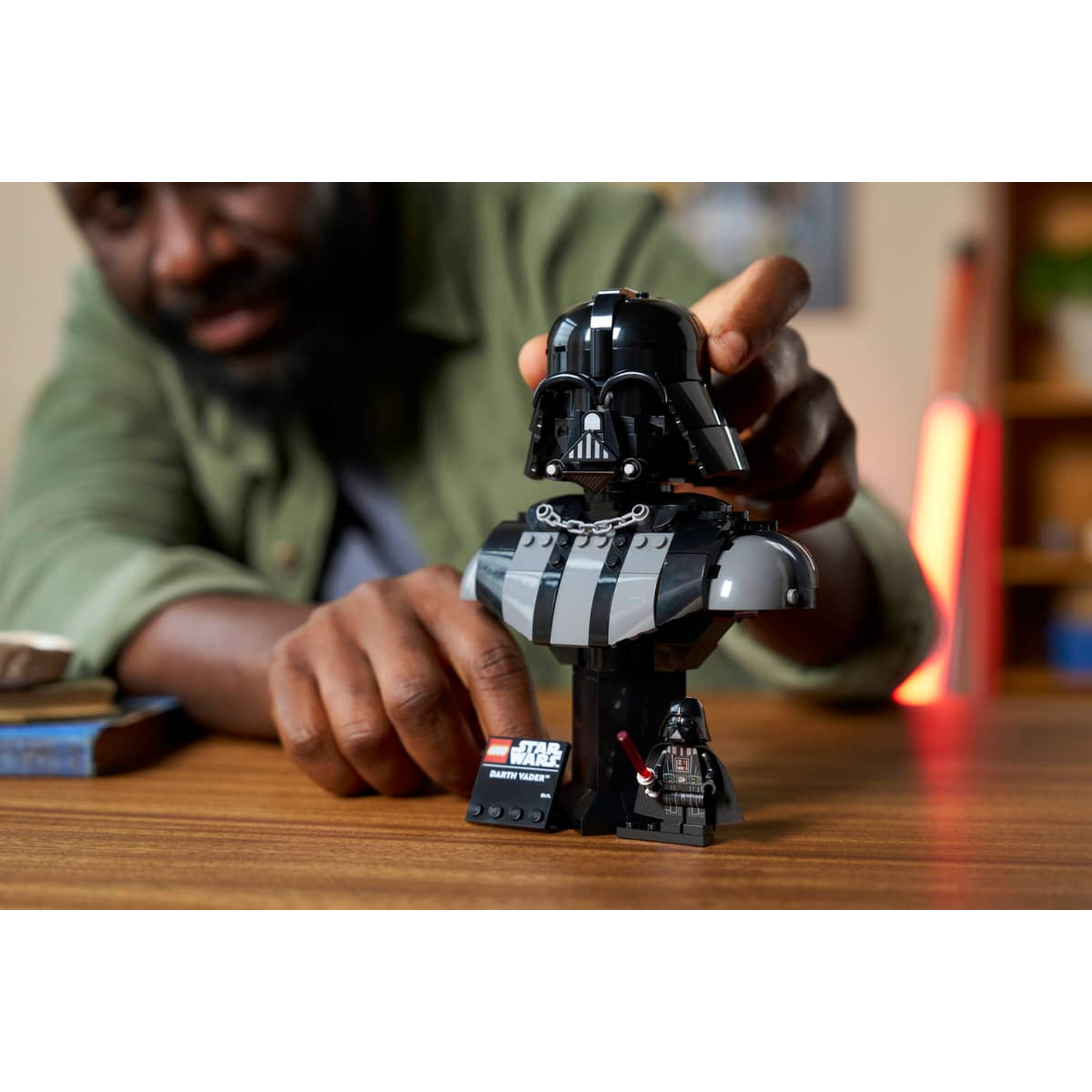 Man building Darth Vader Lego bust. A Lego Darth Vader minifigure stands nearby.