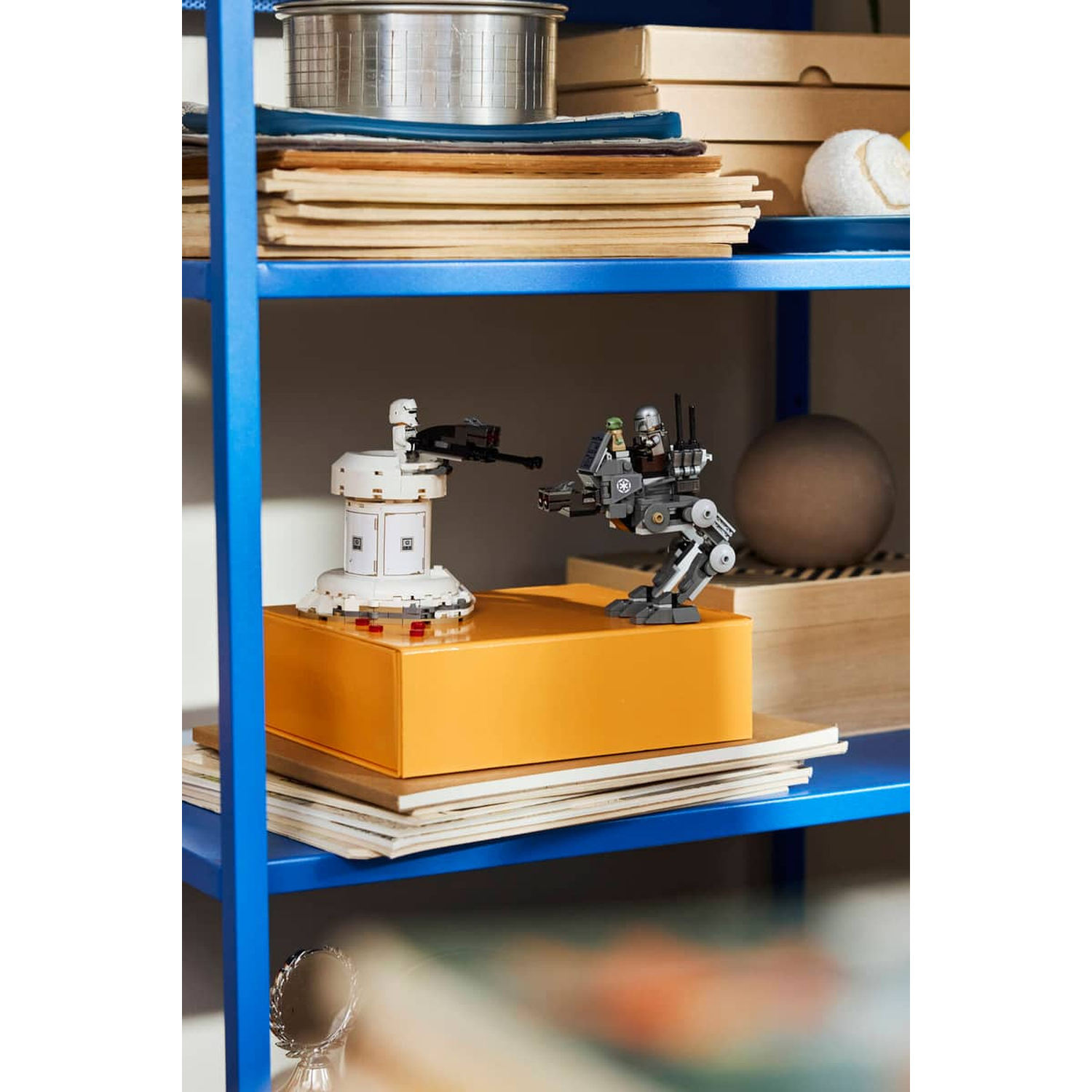 A white Lego turret and a gray Lego robot stand on an orange box.