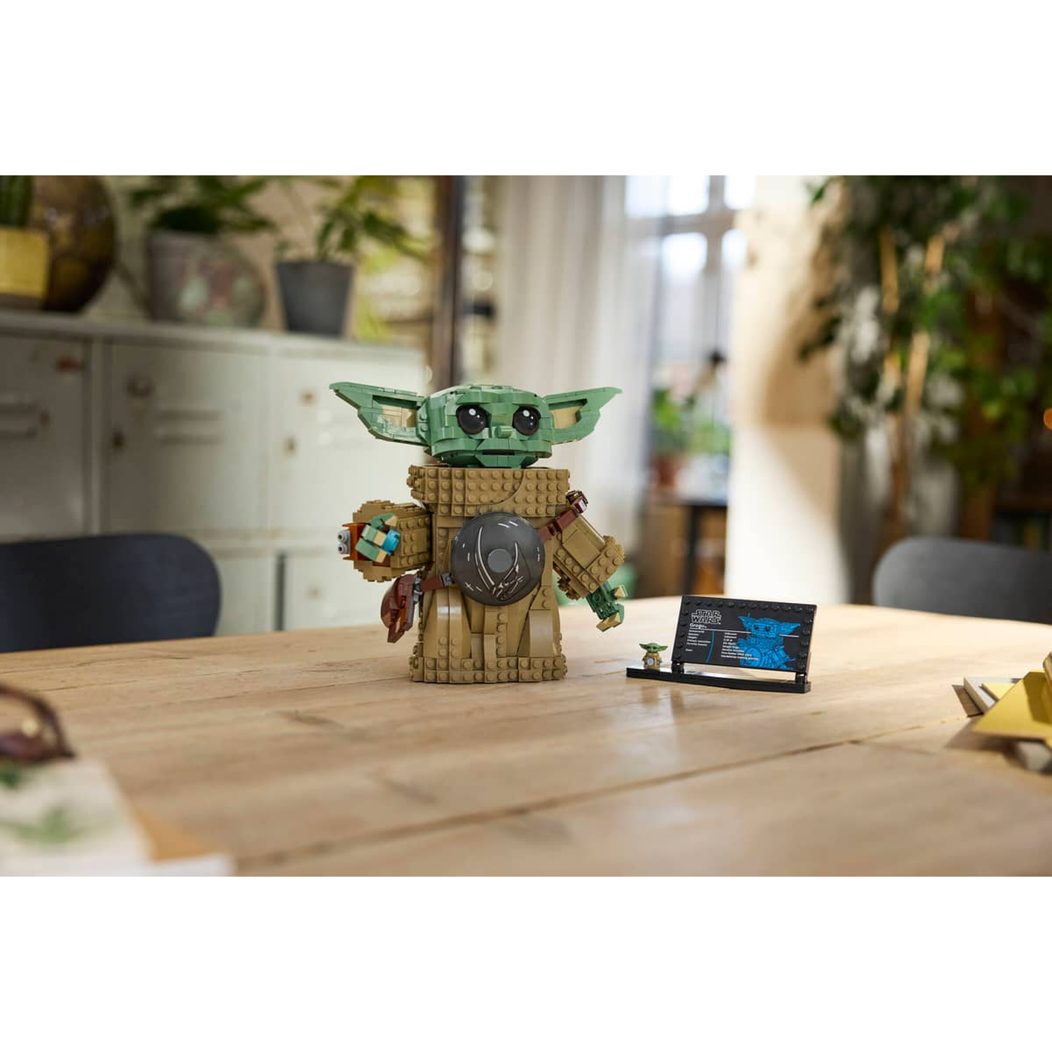 Een Lego-model van Baby Yoda op een houten tafel met een informatiekaart.