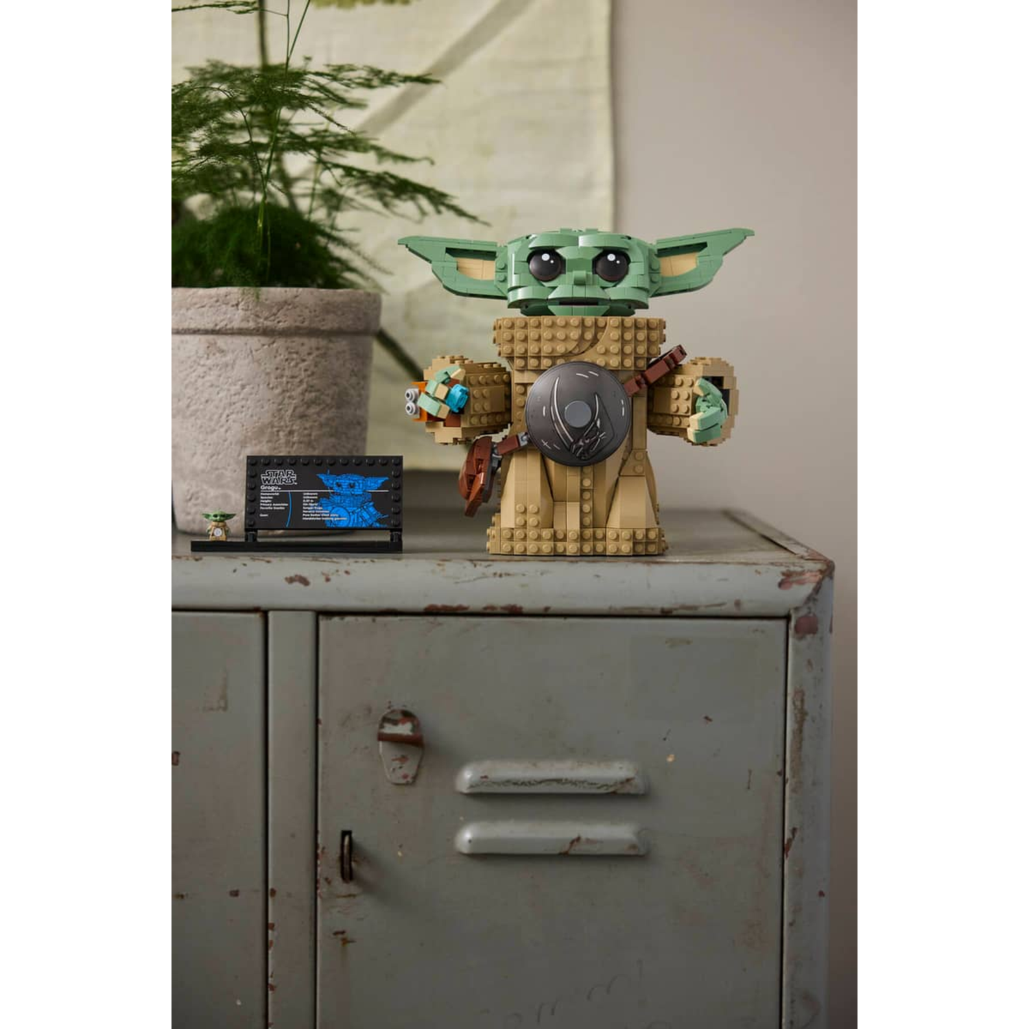 Een Lego-model van Grogu met informatiebord op een vintage metalen kluisje.