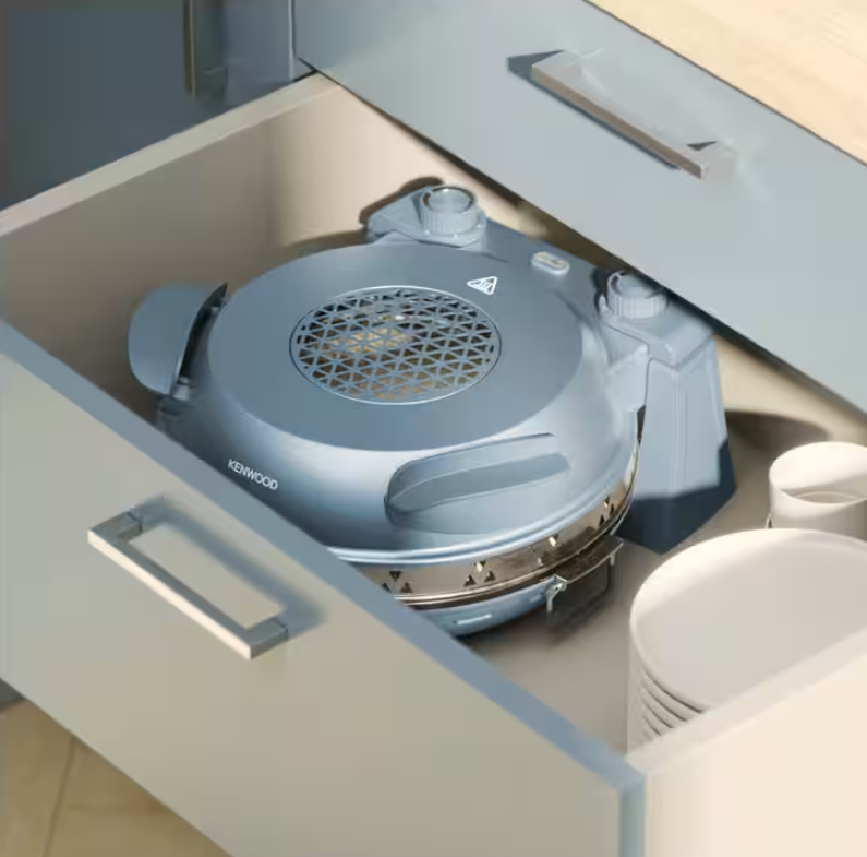Elettrodomestico Kenwood grigio in un cassetto con piatti bianchi accanto.
