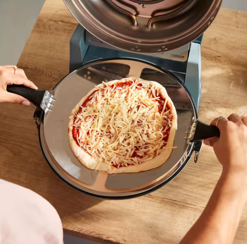 Una persona mette una pizza cruda con formaggio in un forno.