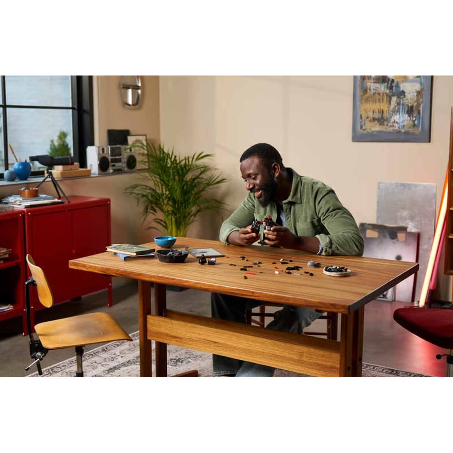 Man bouwt Lego aan een houten tafel. Kleine Lego-onderdelen liggen verspreid.