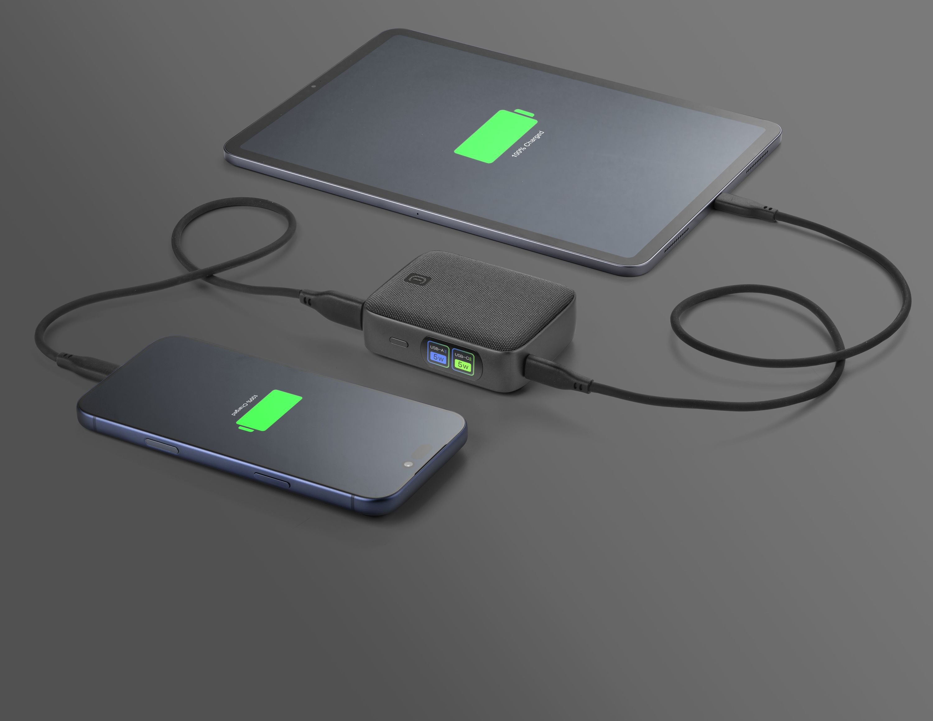 Bir powerbank, bir akıllı telefonu ve tableti şarj ediyor. Her iki cihaz da %100 şarj gösteriyor.