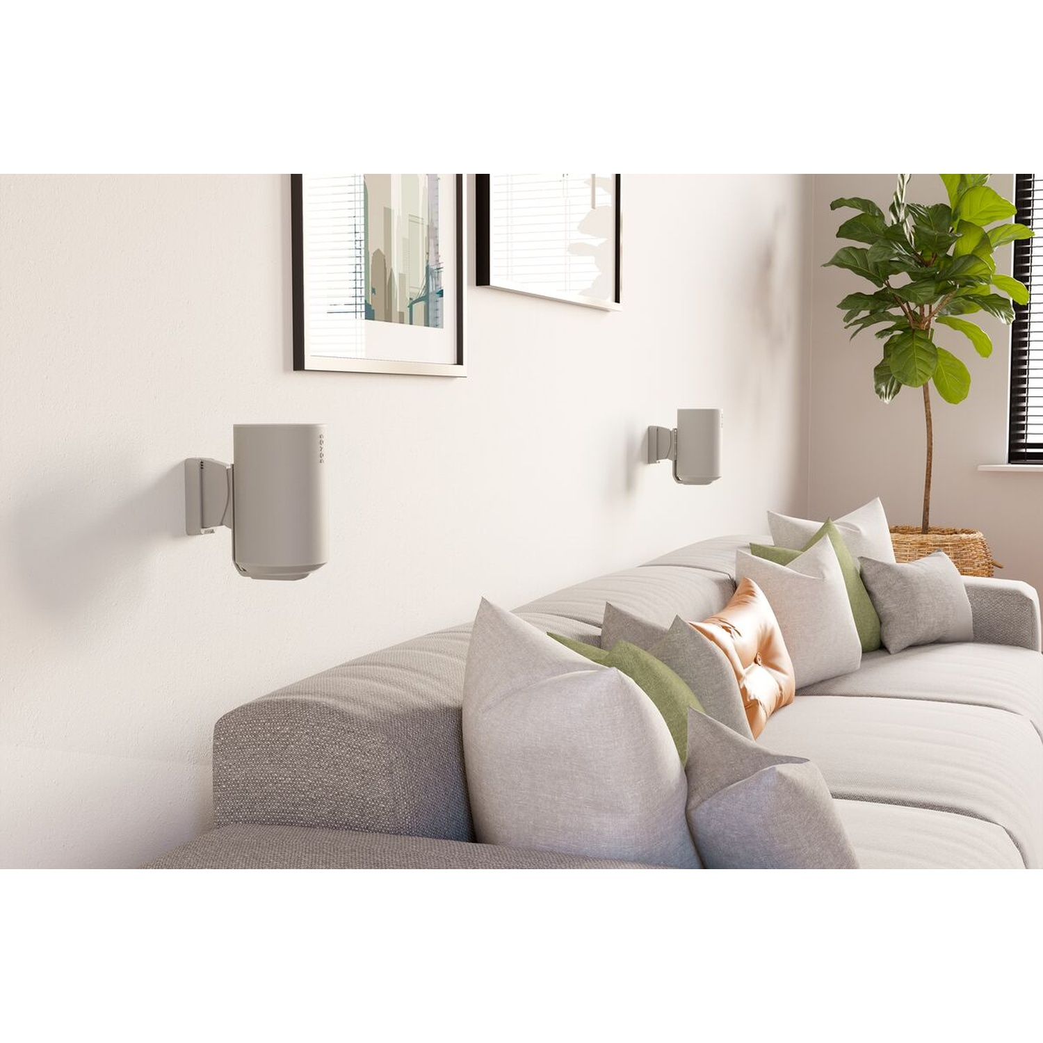 Haut-parleurs gris montés au mur au-dessus d'un canapé avec coussins. Une plante en pot à droite.