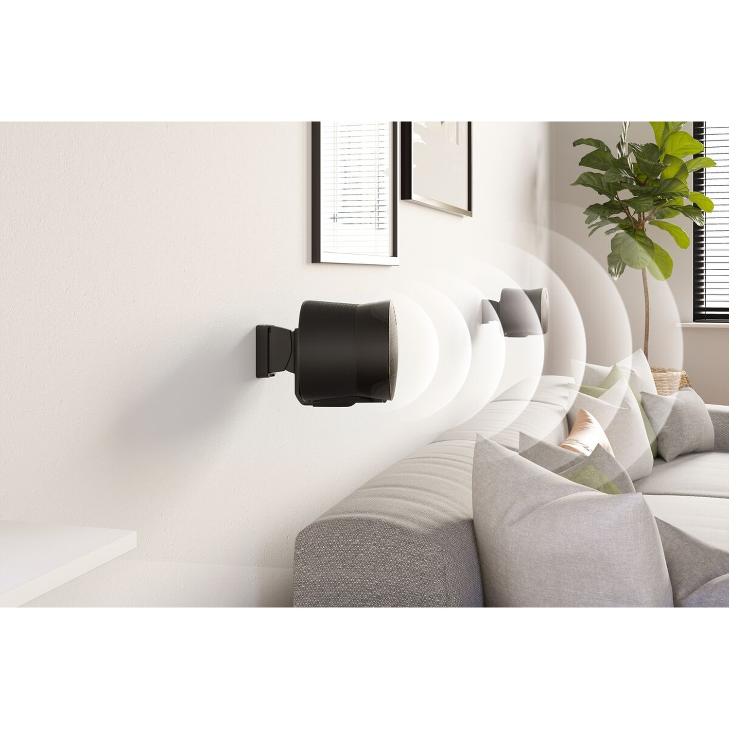Haut-parleurs noirs fixés au mur blanc au-dessus d'un canapé.